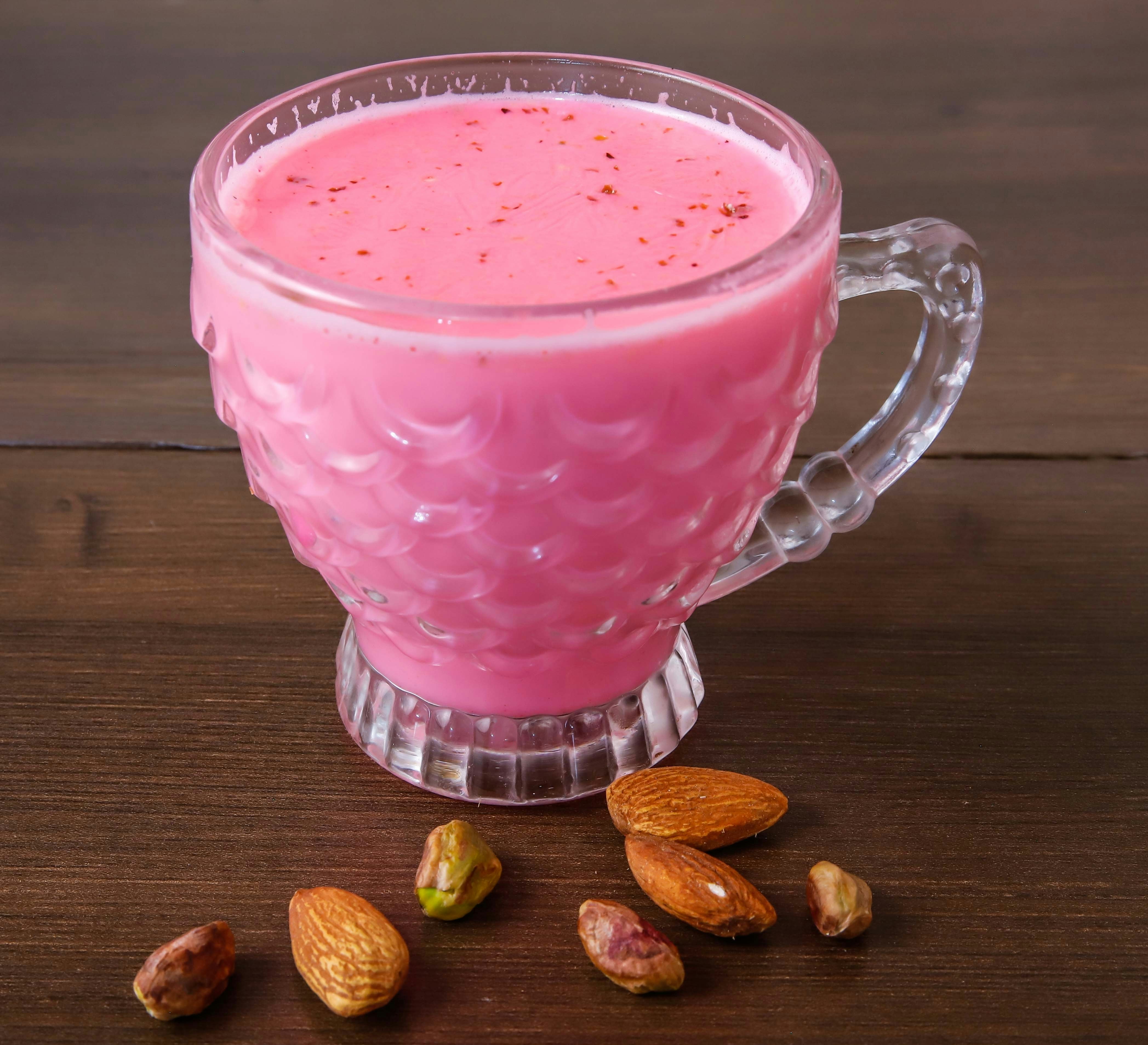 A cup of tea with a pink hue served in a glass.