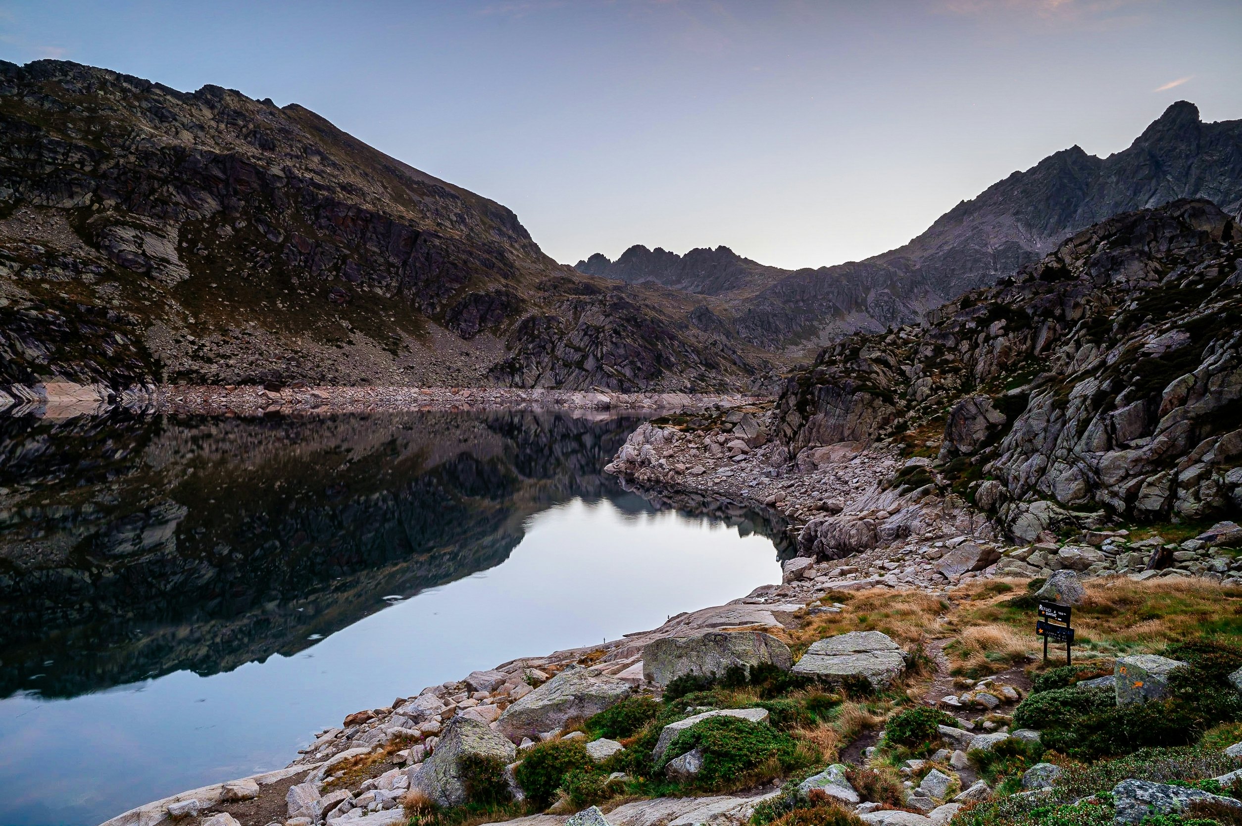 A lake at dusk with mountains surrounding