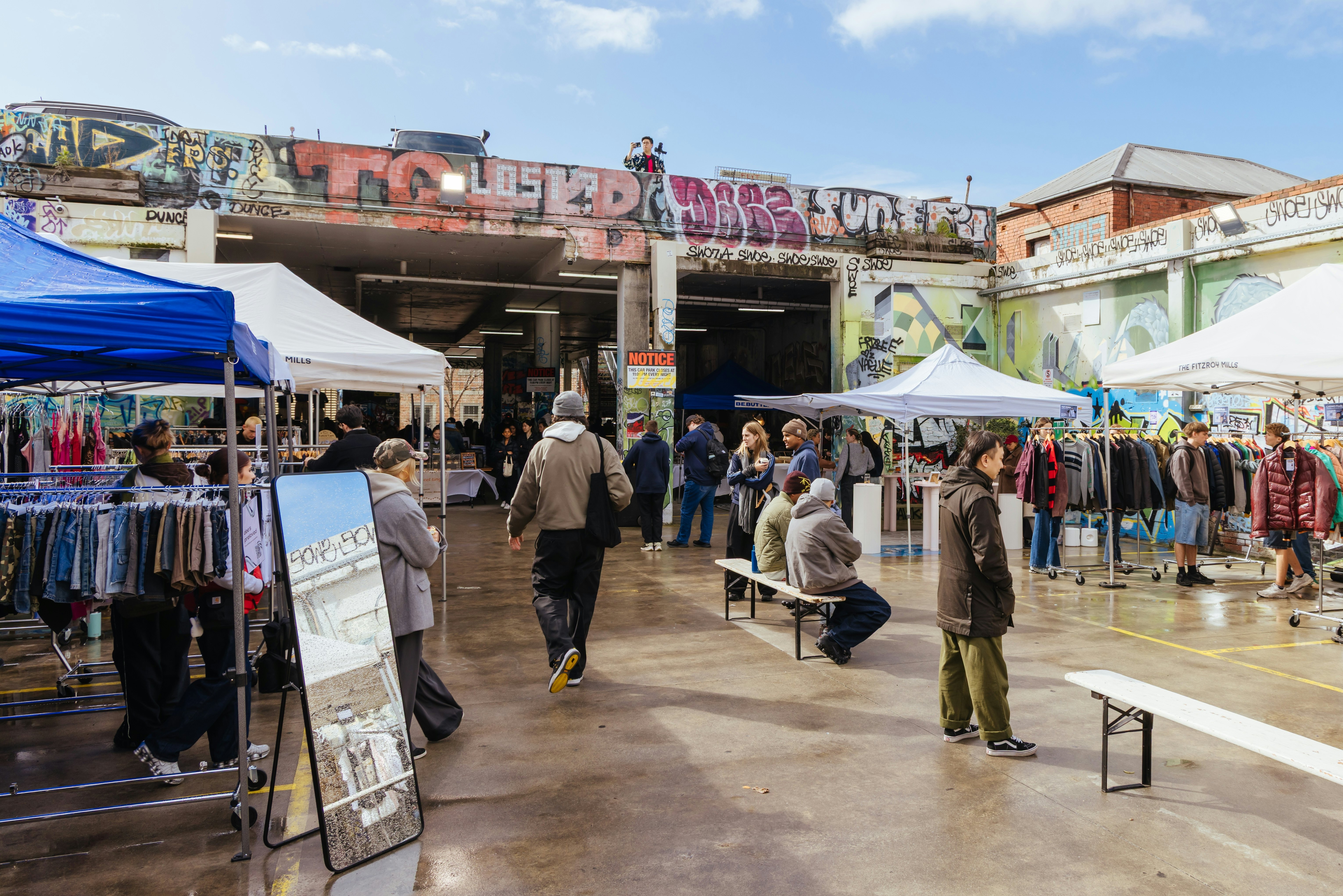 People browse open air stalls at a market on a wet day.