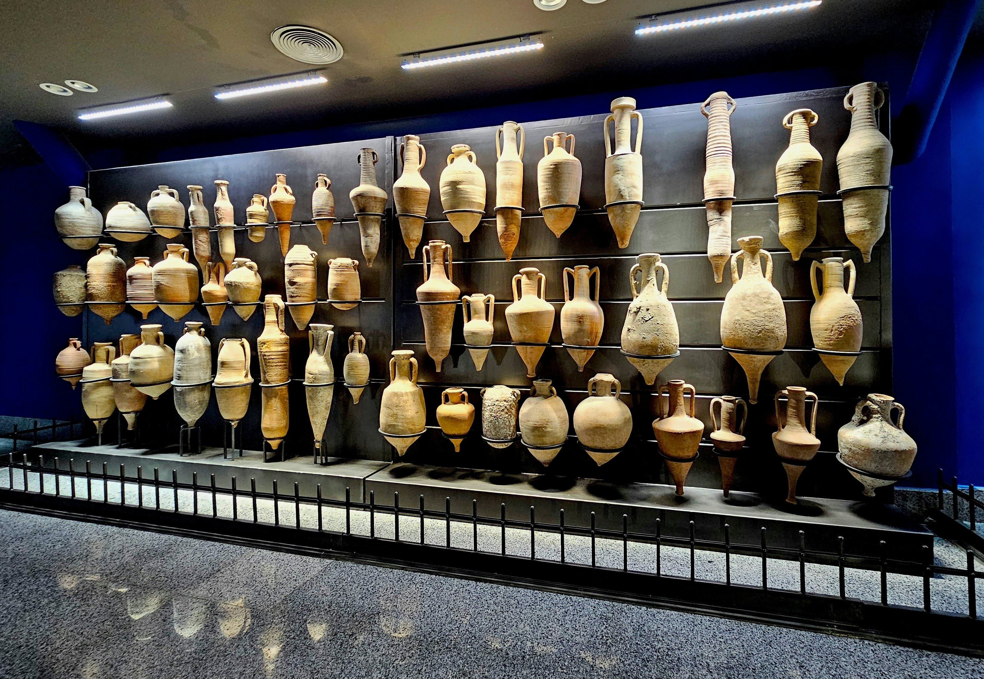 A collection of amphorae installed in a display case in a museum in Egypt.
