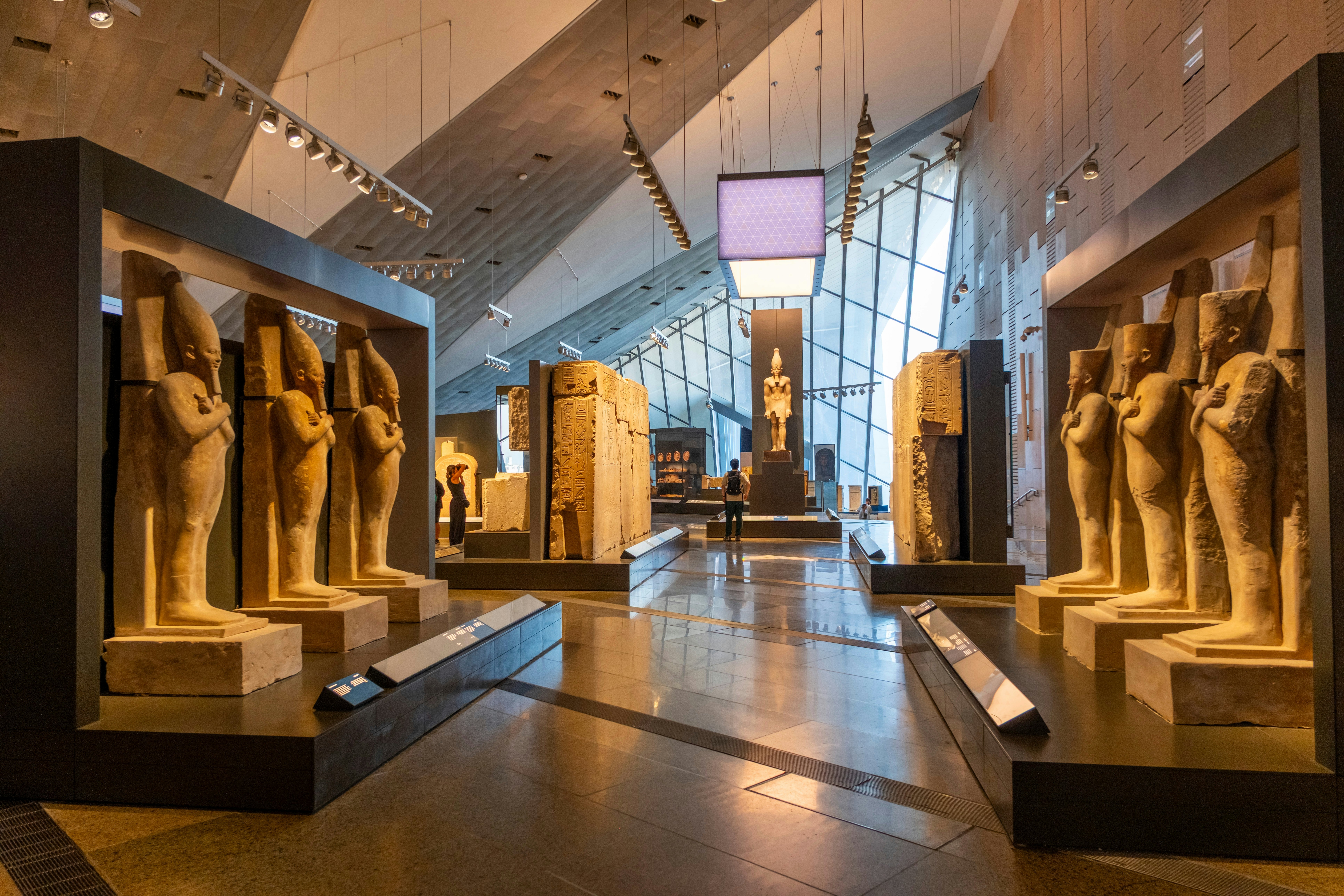 A large exhibition room within a museum lined with stone statues and large engraved stones.