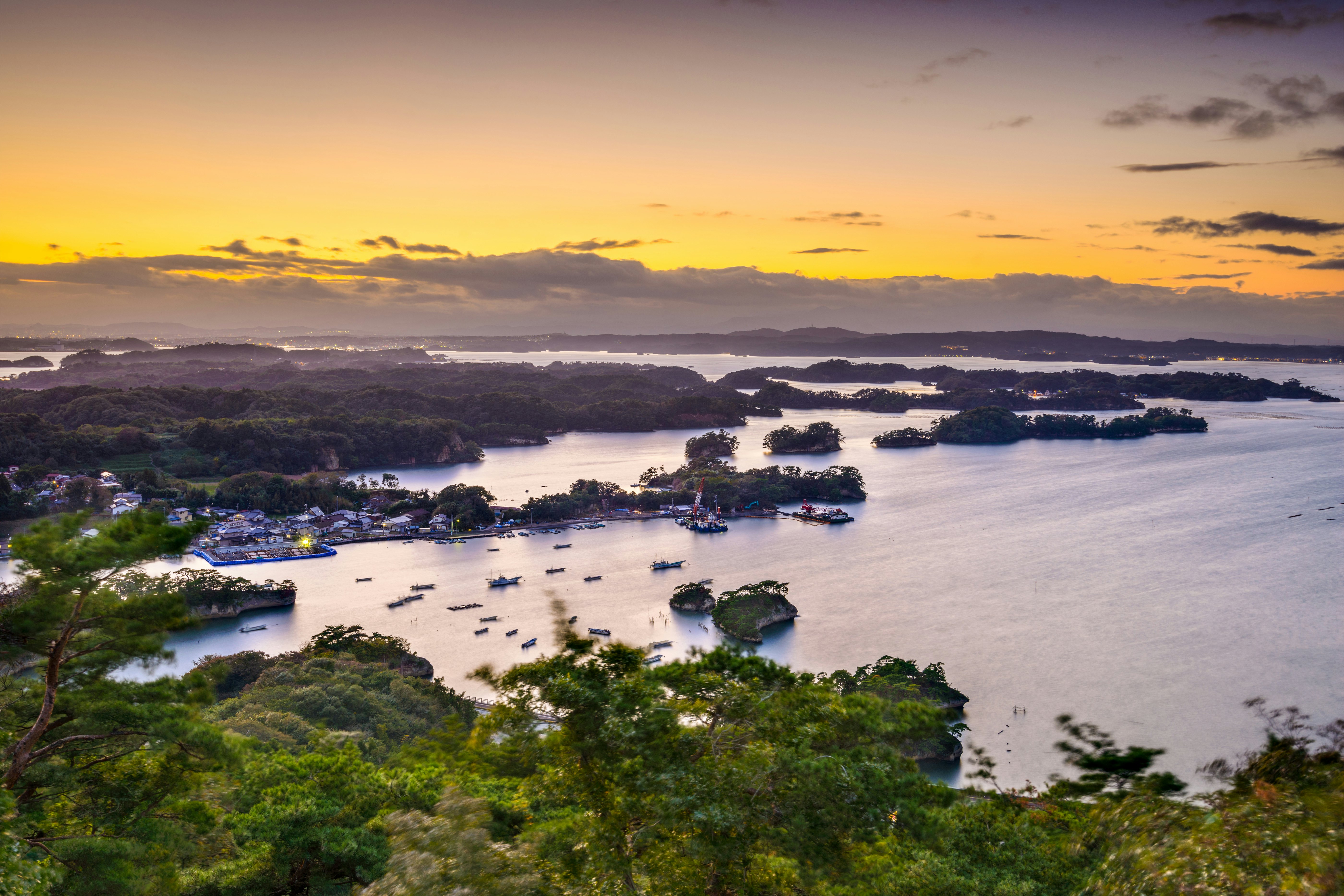 Sunset over a series of small islands. Boats are docked in the sheltered cover.