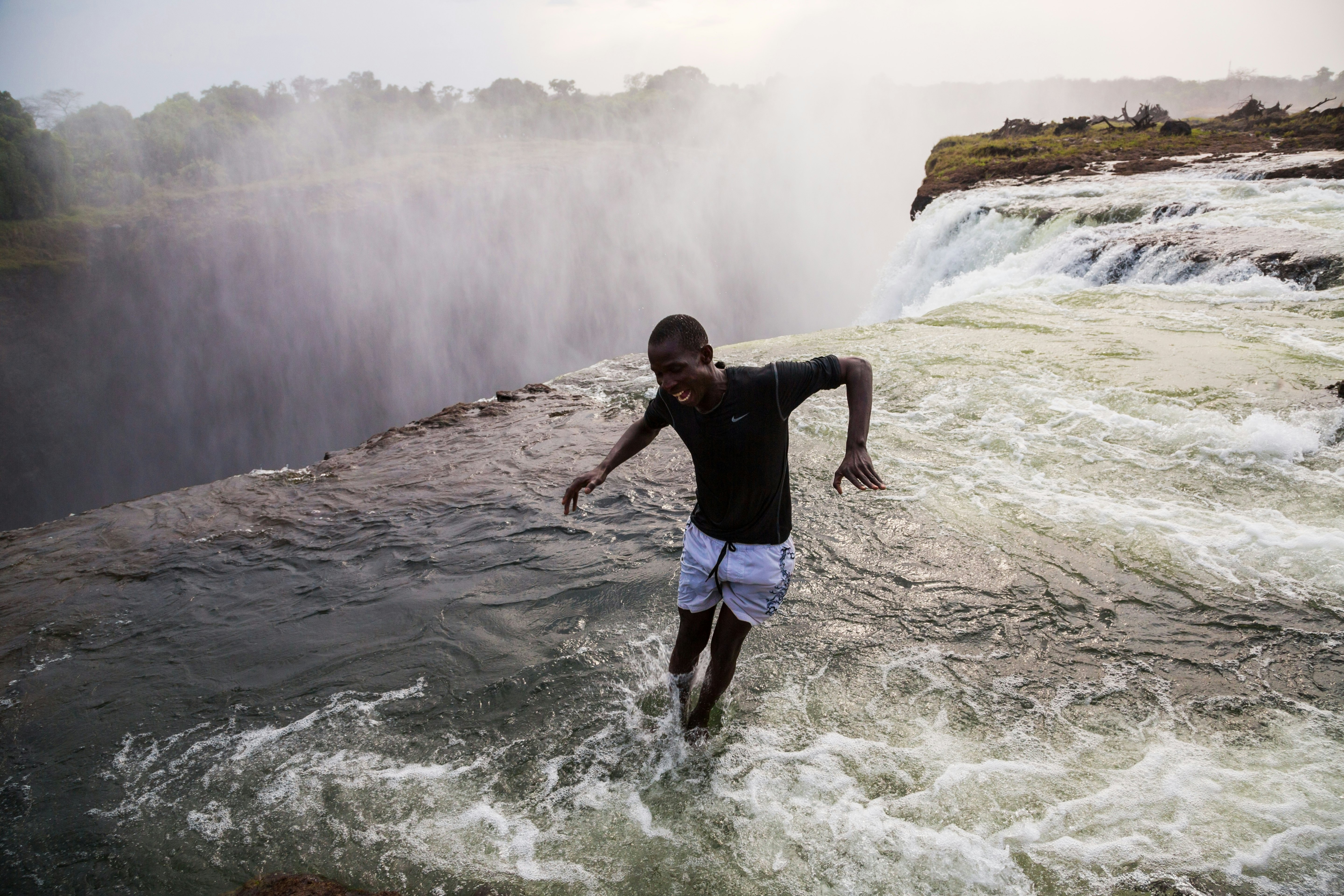 A man jumping into the water at the naturally formed 'Devil's Pool' at Victoria Falls.