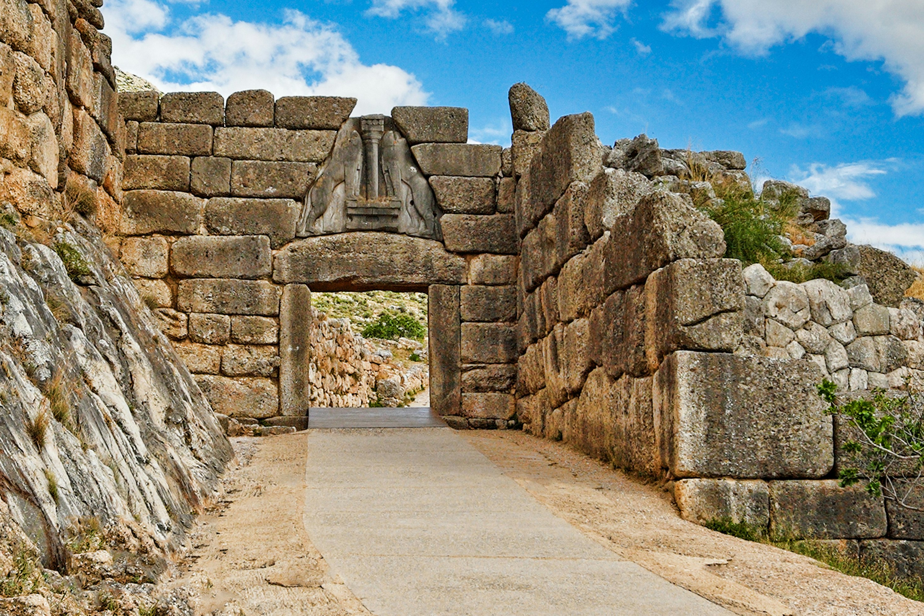 a path through an ancient walled building with blue sky above