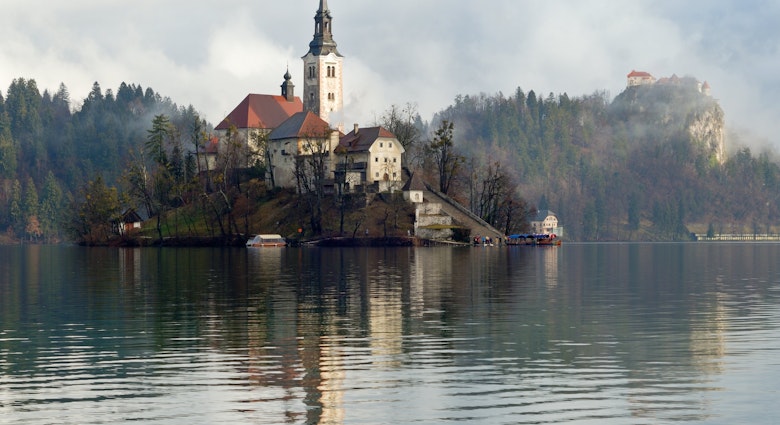 A church located on an island in Lake Bled with the castle in the background, Slovenia, License Type: media, Download Time: 2025-01-29T21:38:03.000Z, User: rhylton_redventures, Editorial: false, purchase_order: 56530 - Guidebooks, job: Lonely Planet WIP, client: Lonely Planet WIP, other: Rhianydd Hylton
