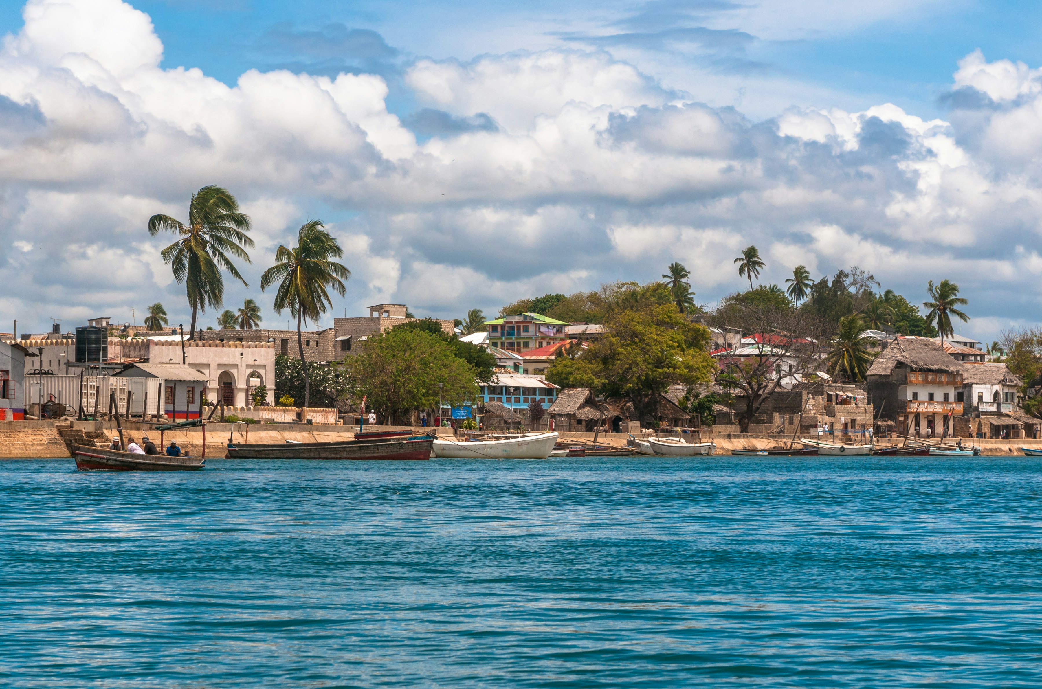 A small low-rise town on the edge of the ocean, with fishing boats lining the shore.