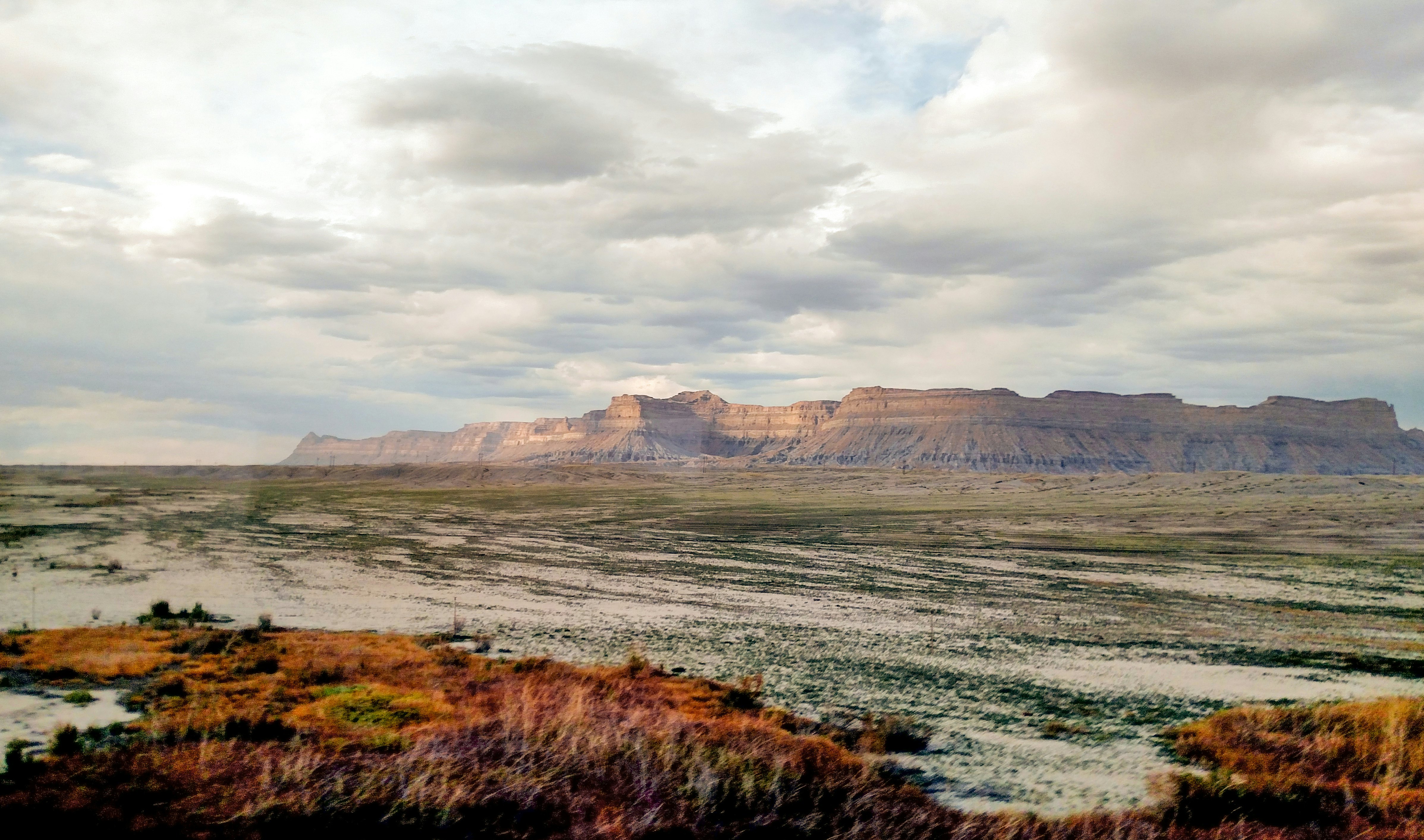 Vast plains with mountains rising up in the distance under a cloudy sky