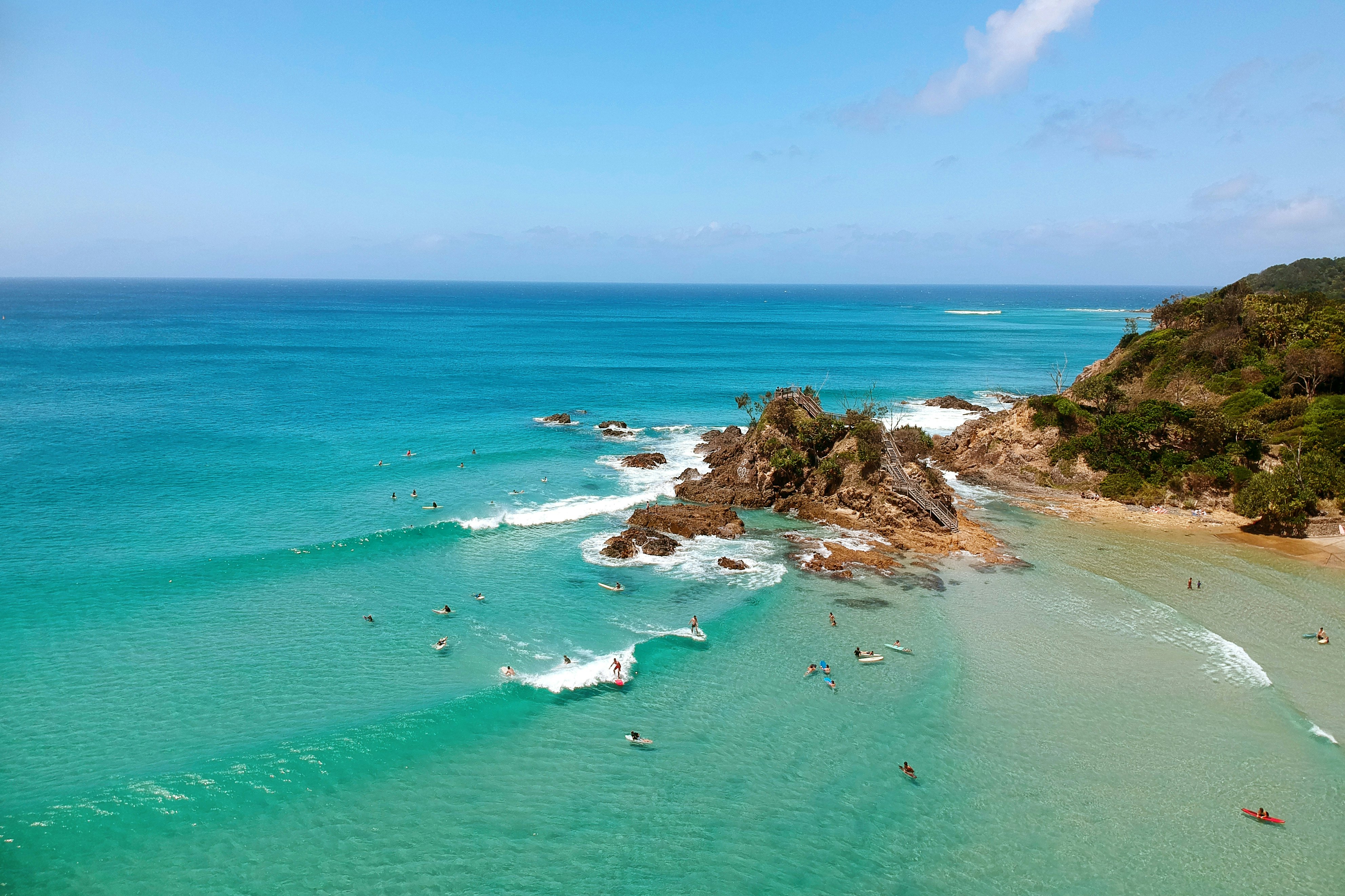 People surfing by rocks jutting out into the ocean