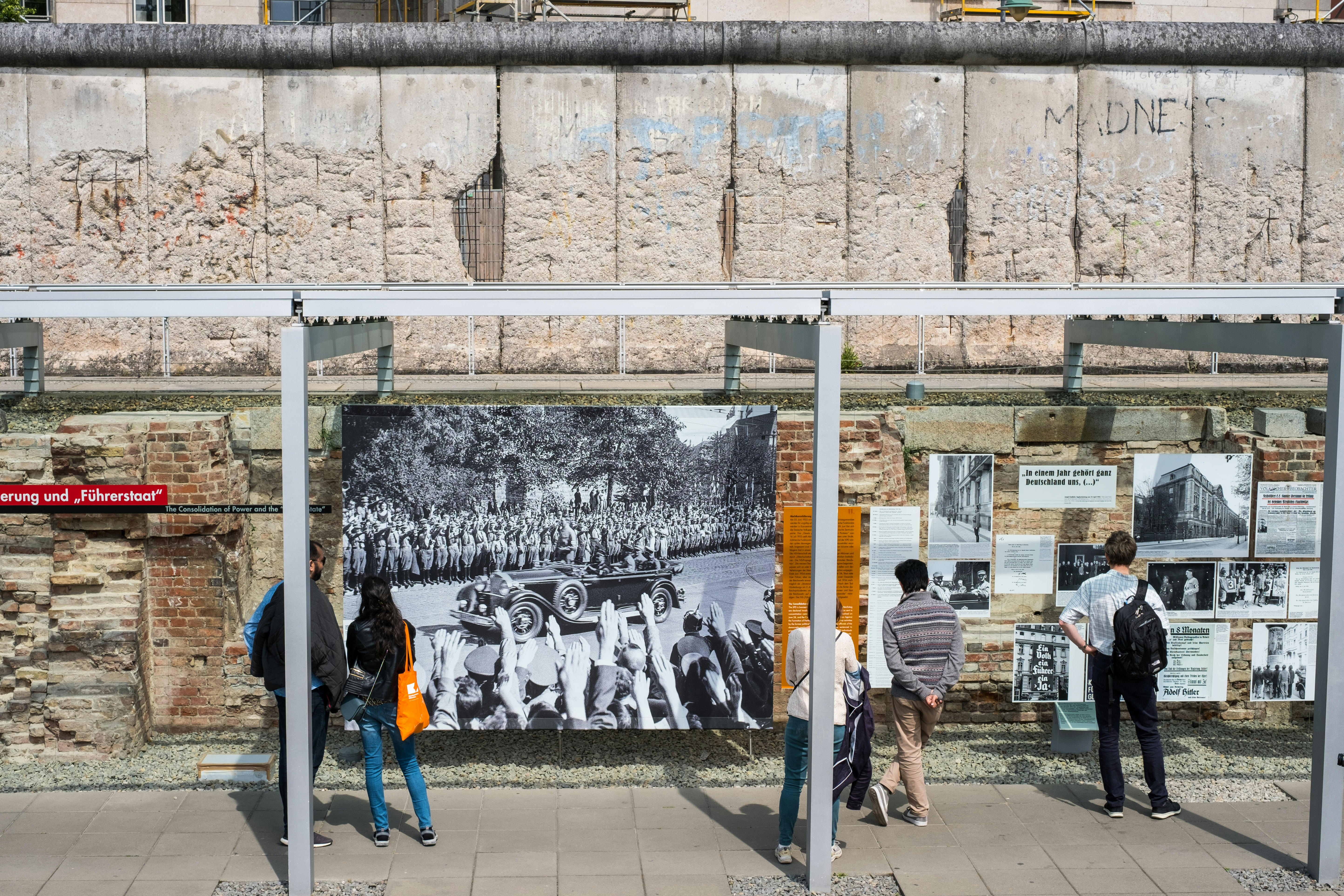 People read displays on the wall of an outdoor exhibition space.