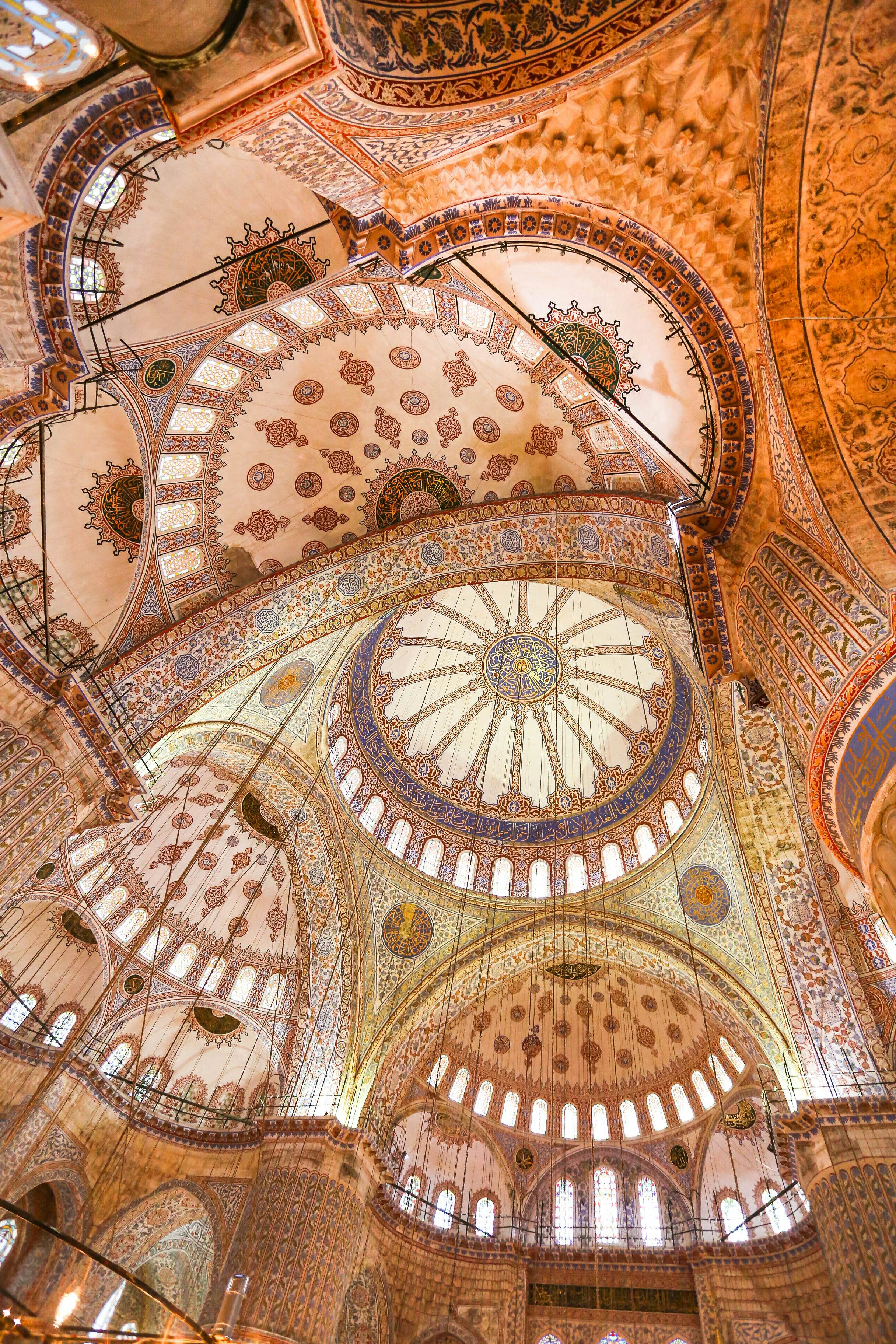 Interior of a mosque, looking up at ornate, rounded ceilings.