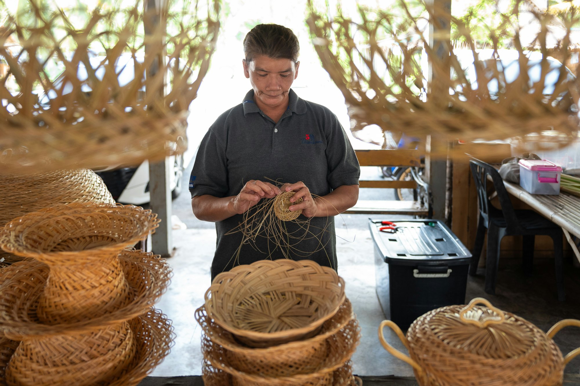 A weaver in their studio creating baskets from dried palm fronds.
