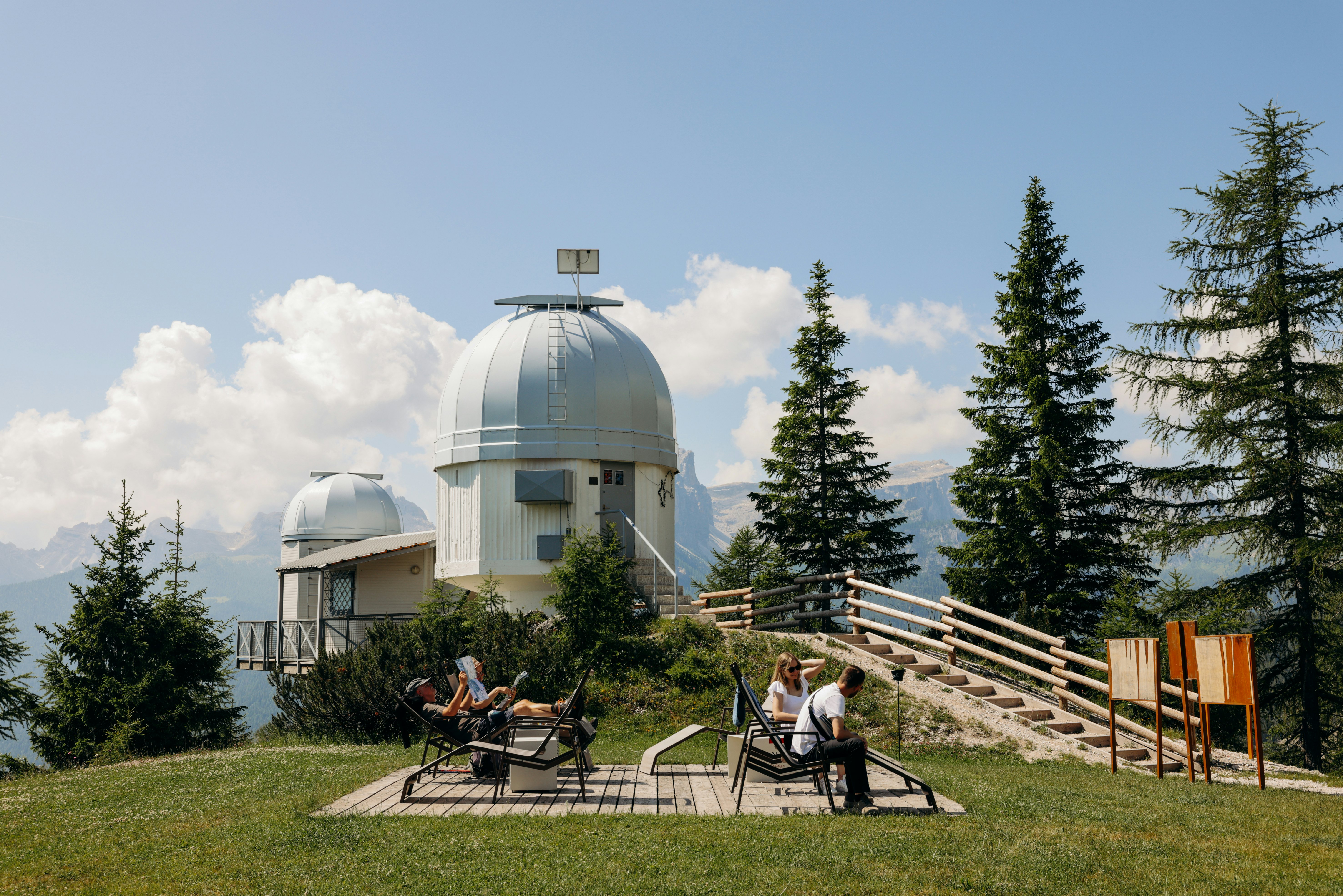 People enjoy the sun with a view of the Observatory in Cortina d'Ampezzo, Italy