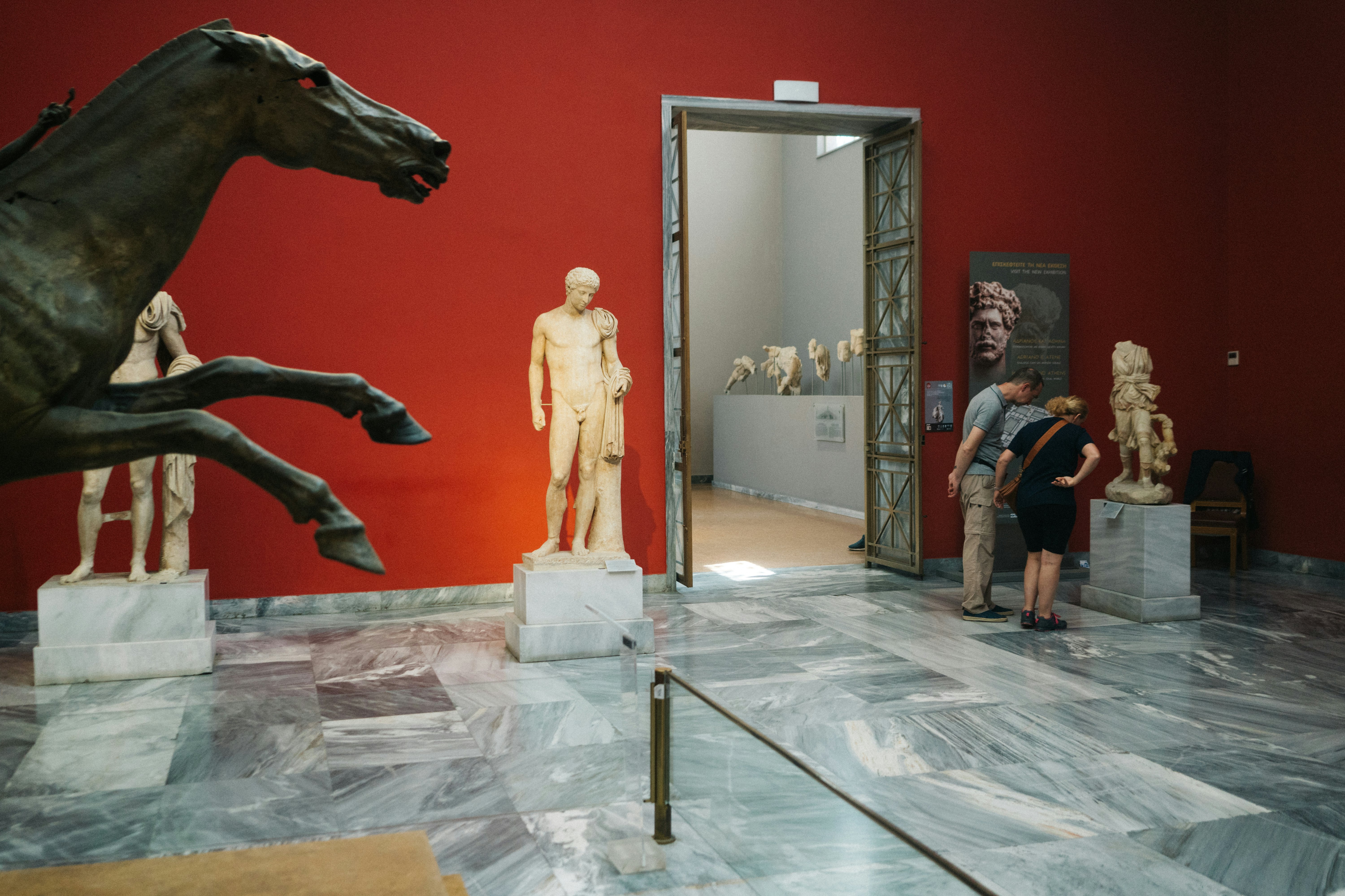 Marble statues in front of a red wall at the National Archaeological Museum, Athens