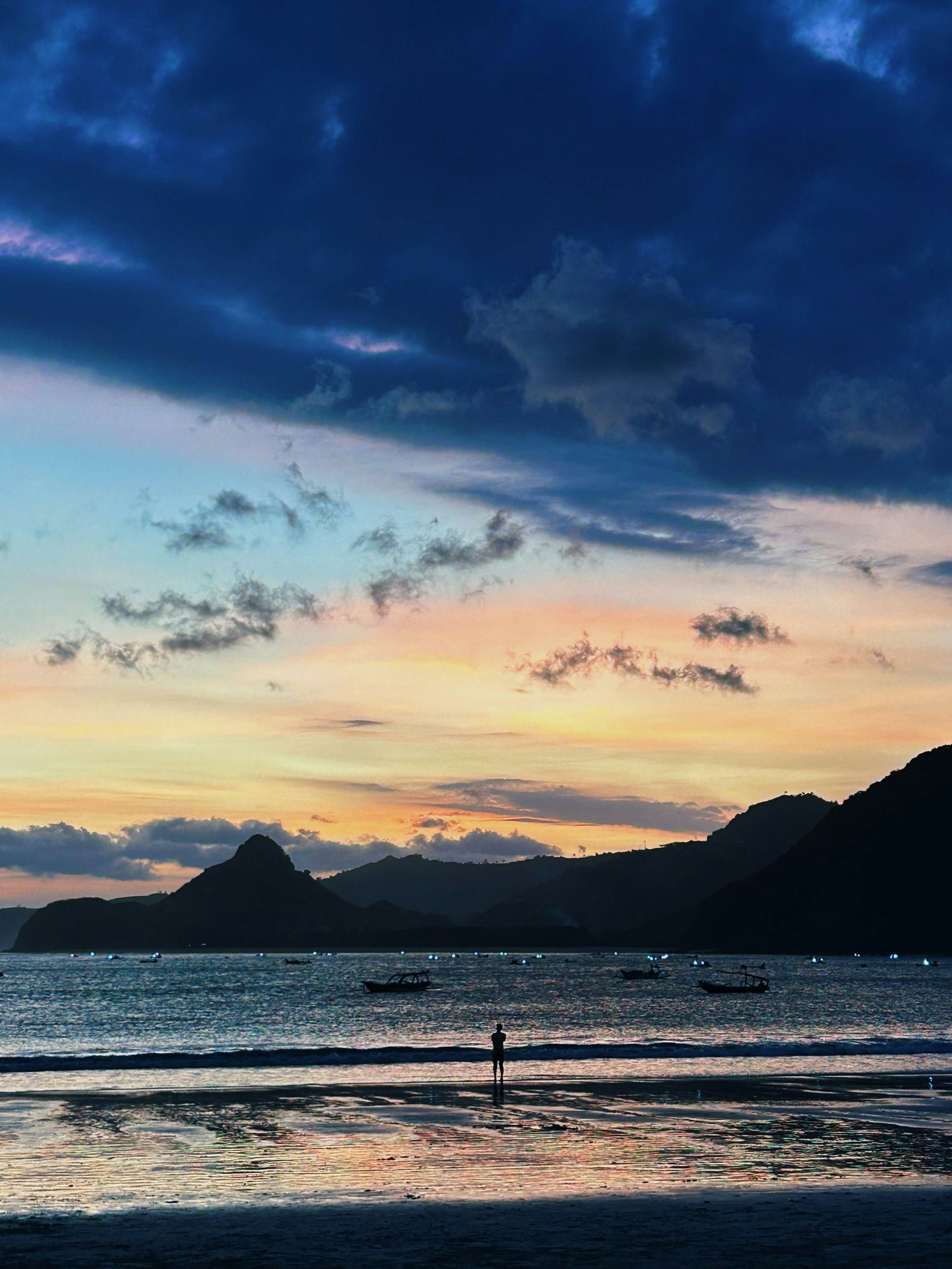 A sunset over a beach casts colorful streaks across the sky. 