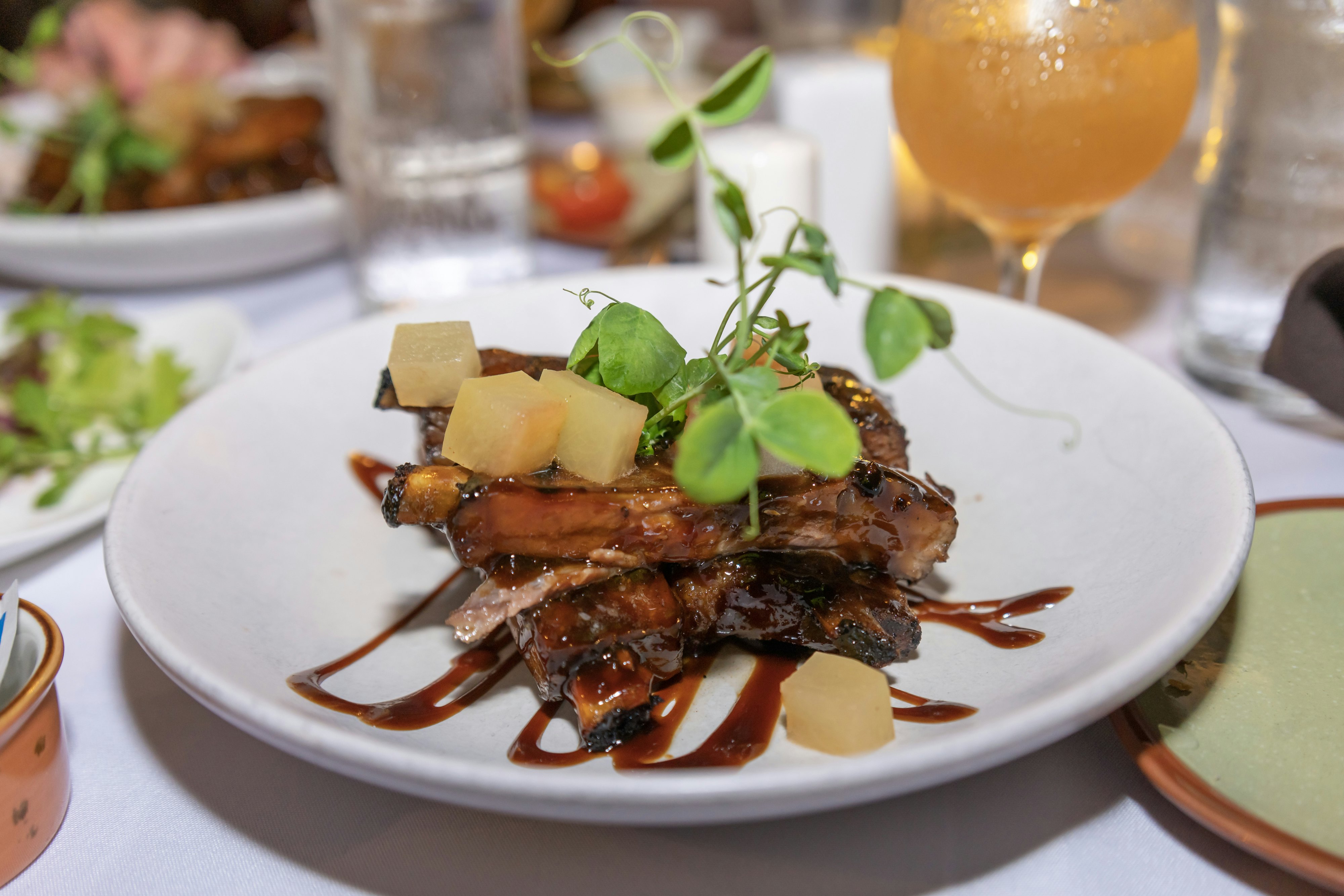 Hawaiian style sticky sweet barbeque ribs with chunks of pineapple and a pea sprout garnish.