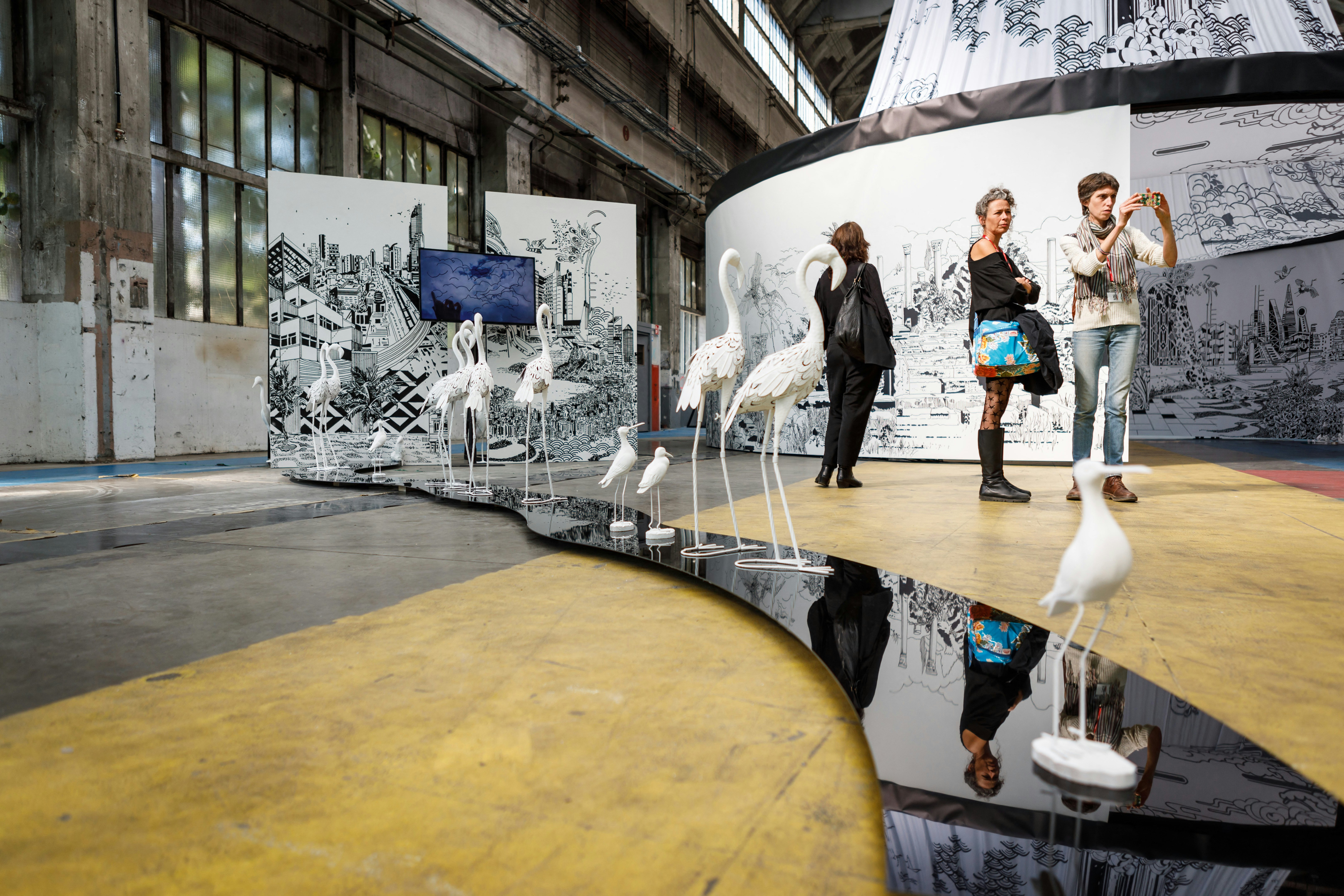 People look at an installation of contemporary art in a transformed industrial space.