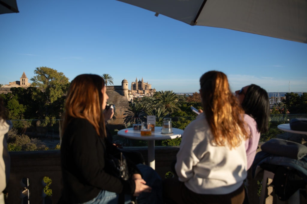 05 December 2024, Spain, Palma: Four women are sitting on the roof terrace of Hostal Cuba, one of the main panoramic terraces in the city of Palma on Mallorca, on a sunny day.