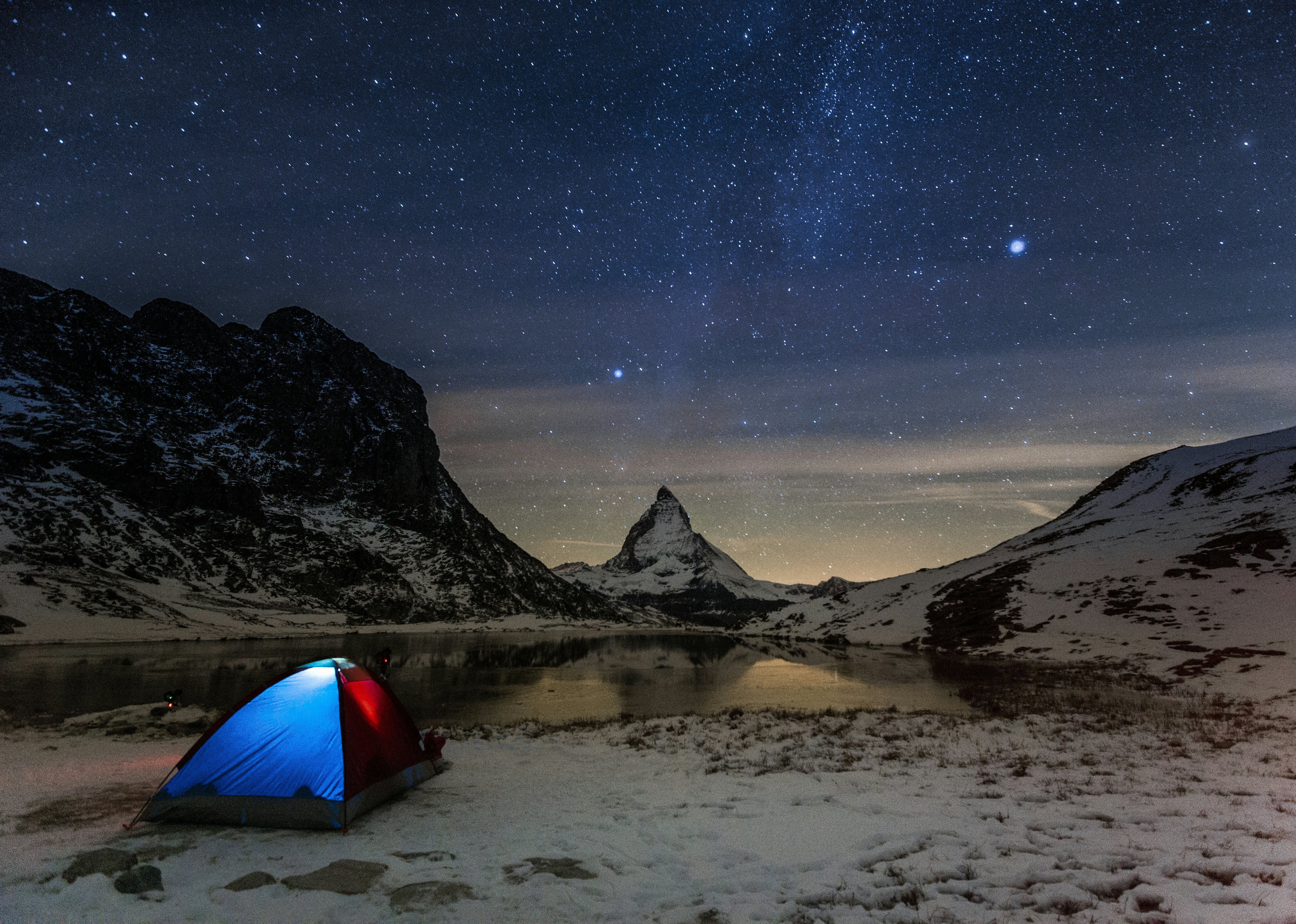An illuminated tent beneath million of stars over the Matterhorn in Switzerland.