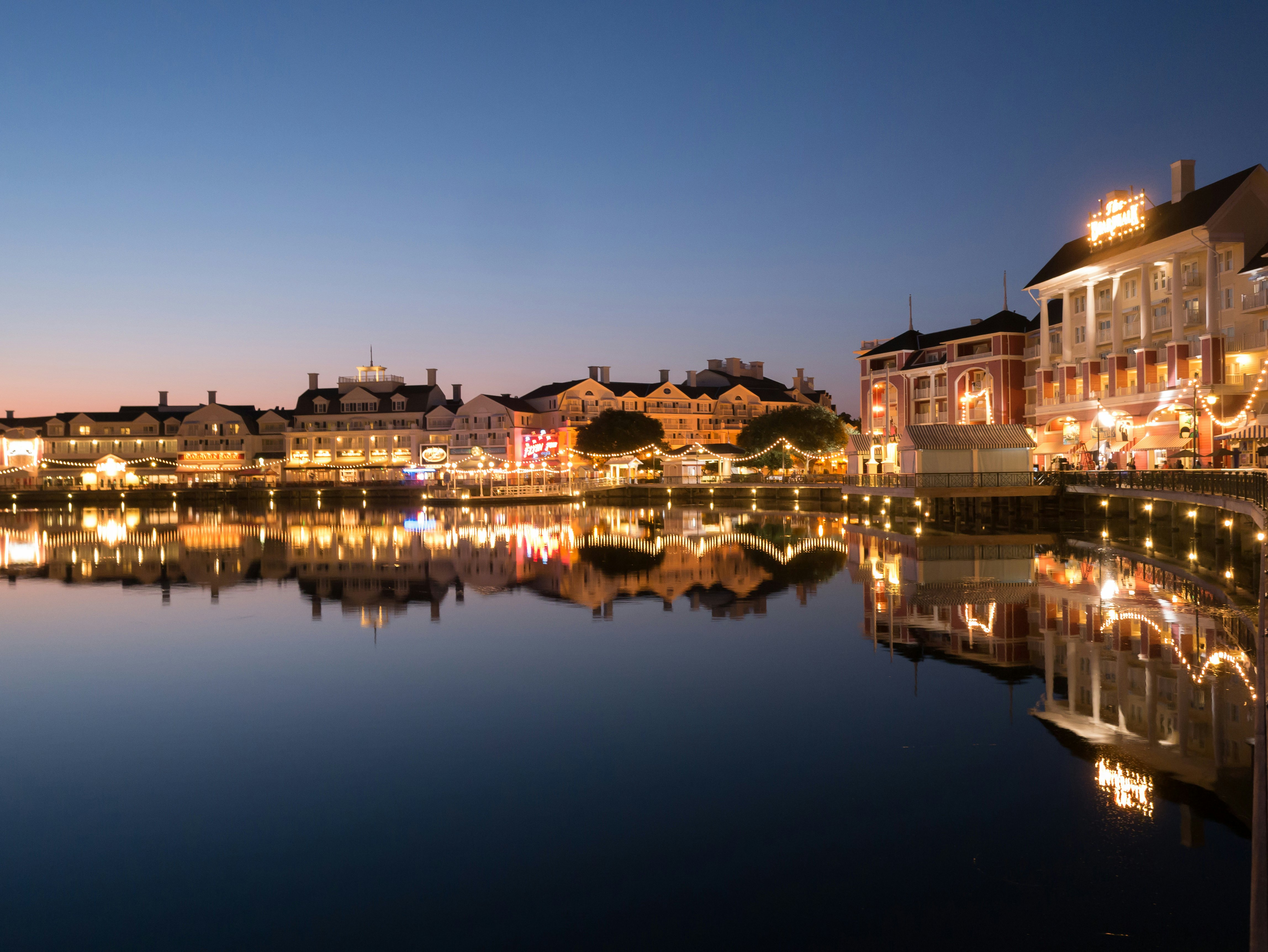 A lakefront promenade lined with mansion-like buildings lit up in twilight