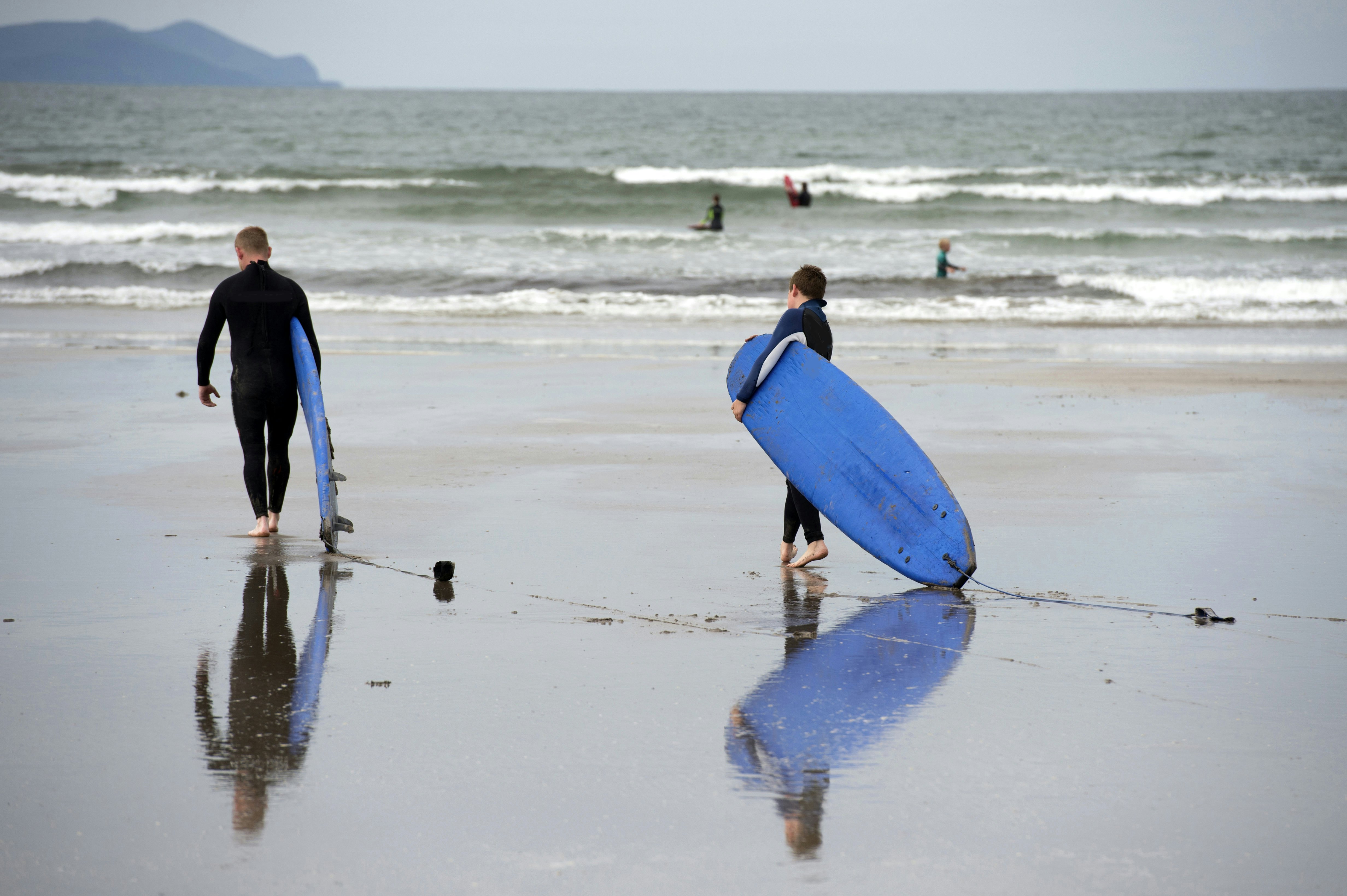Two surfers with surfboards on the sand at Inch Beach on the Dingle Peninsula in Ireland.