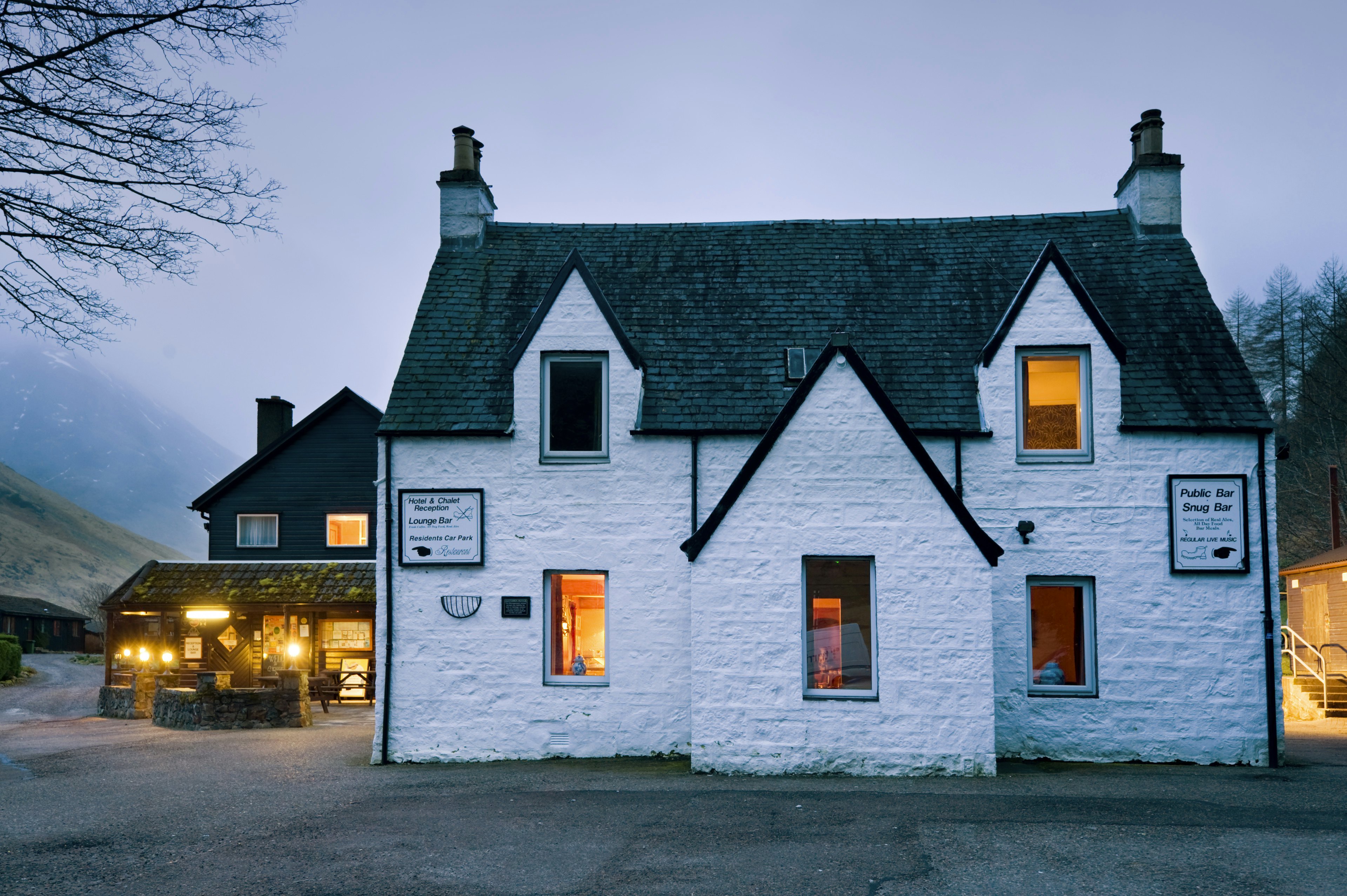 A historic white-painted pub in the countryside is pictured at dusk.