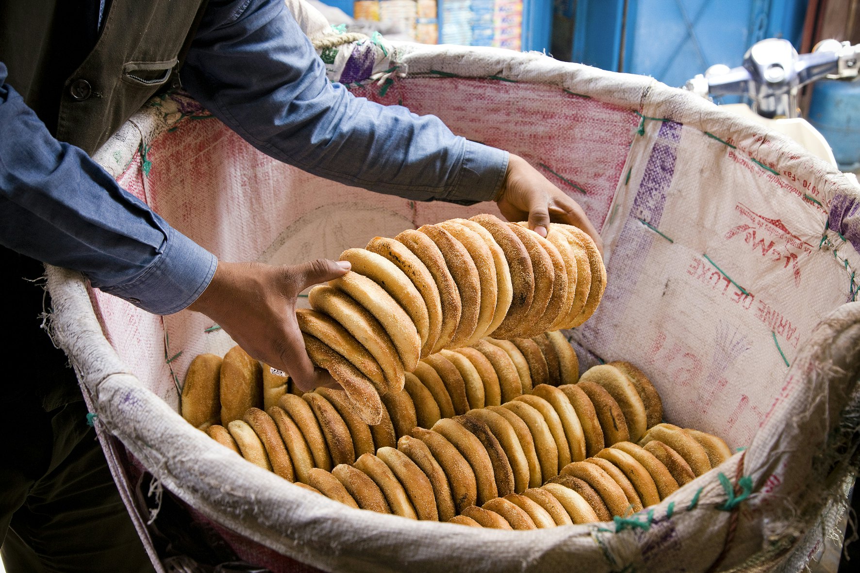 Hands lift a stack of bread out of a large basket.