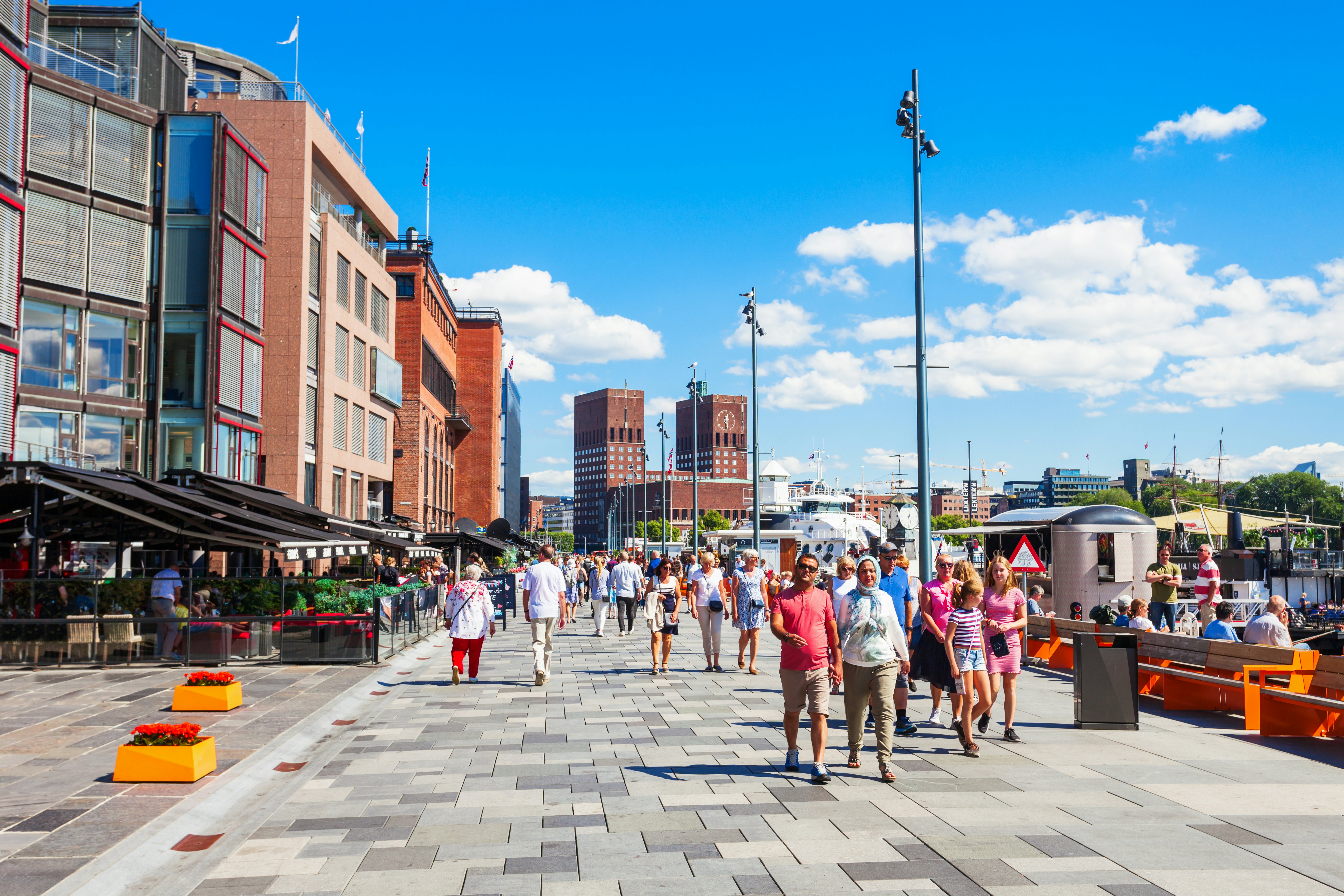 A waterfront pedstrianized area lined wtih bars and restaurants on a sunny day.