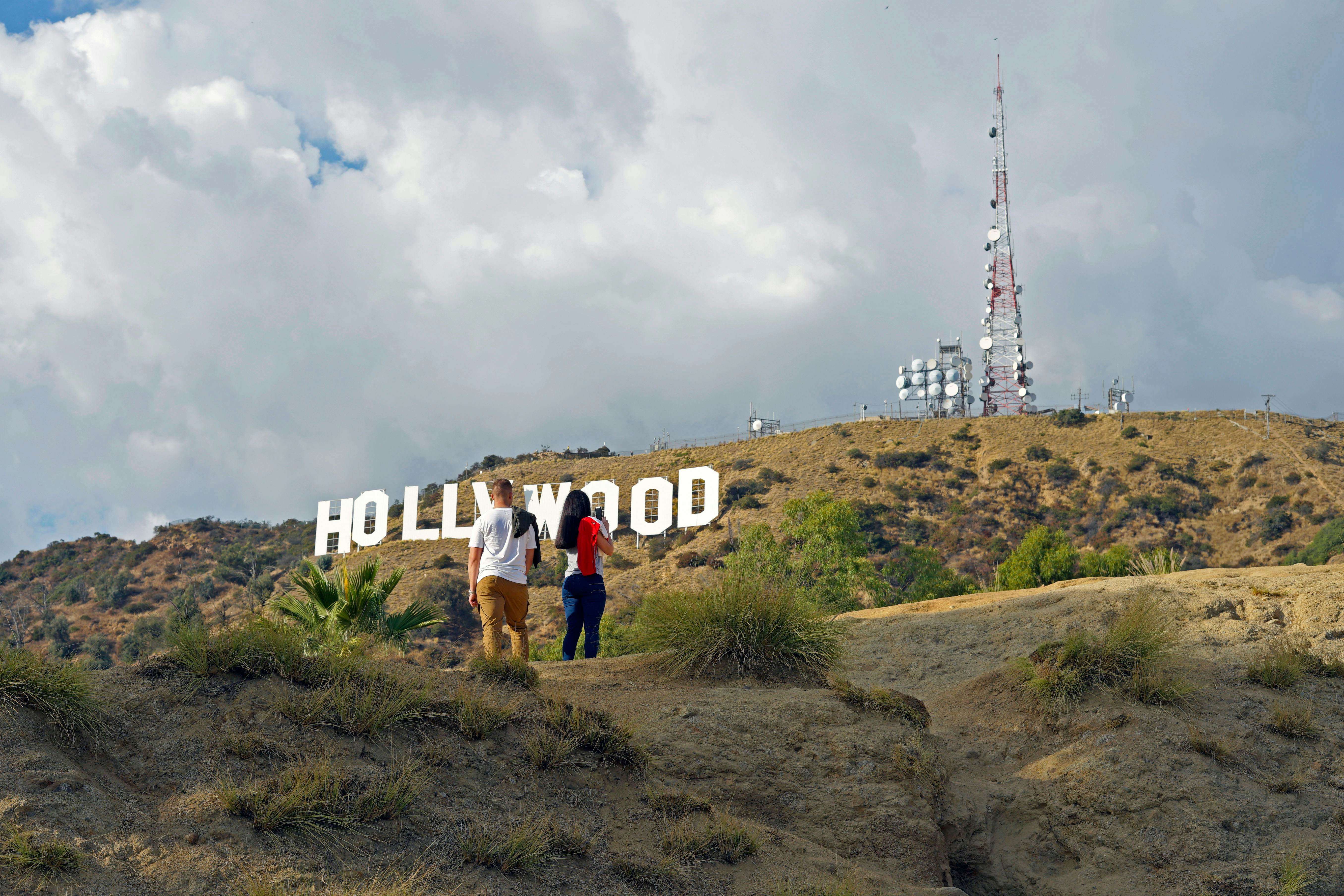 Hollywood, California/ USA  11-21-19 Two young people hiking in Hollywood California's Griffith Park stop to  admire a famous sign in the Hollywood Hills  License Type: media  Download Time: 2024-01-17T14:24:34.000Z  User: bhealy950  Is Editorial: Yes  purchase_order:   