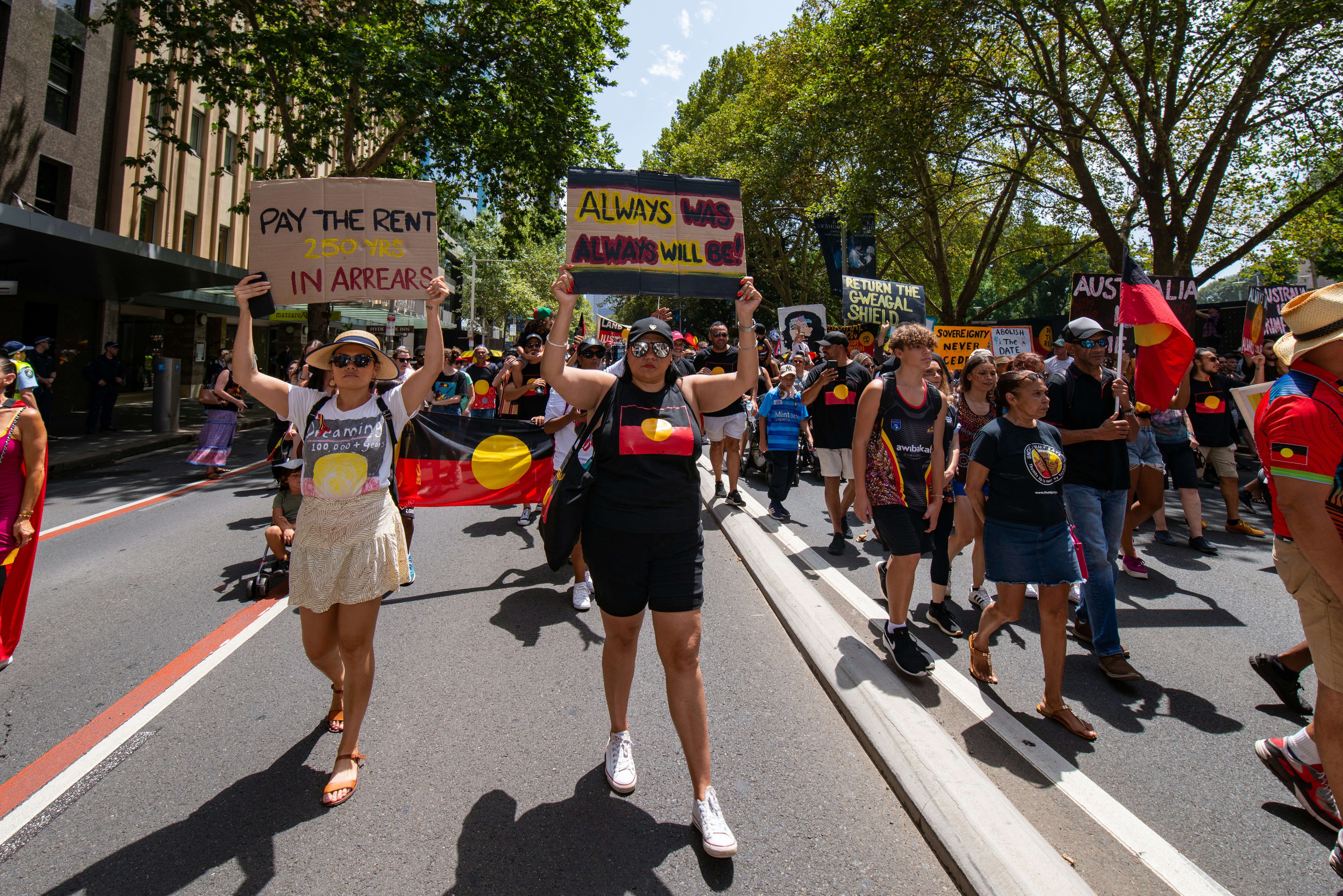Protestors hold flag and placards during a demonstration in a city street.