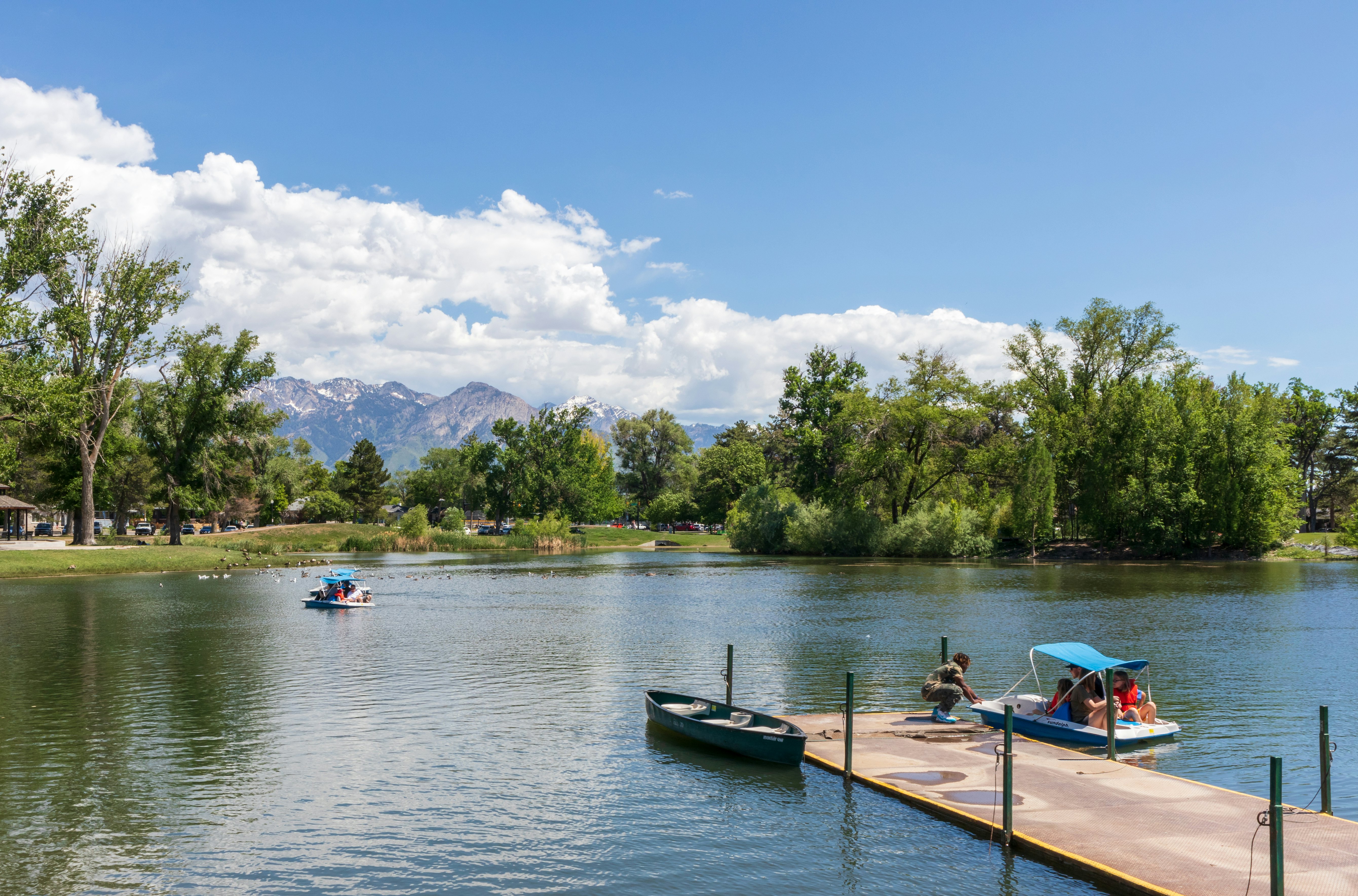 The pond with a boat pier in Liberty Park in downtown Salt Lake City, Utah. People riding on the pedal boats
