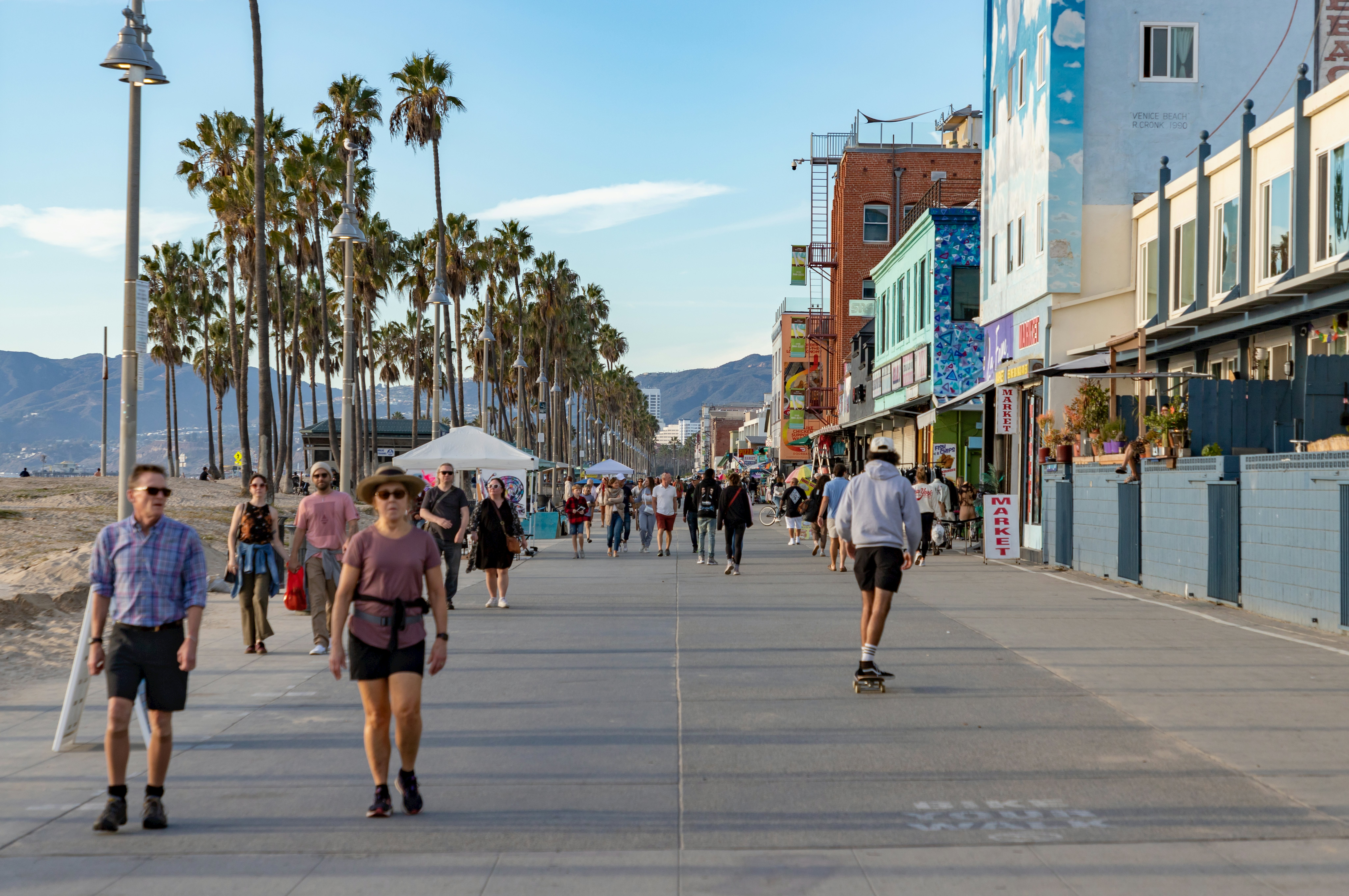 Los Angeles, United States: A picture of the iconic Venice Beach boardwalk with people walking and skateboarding on it.