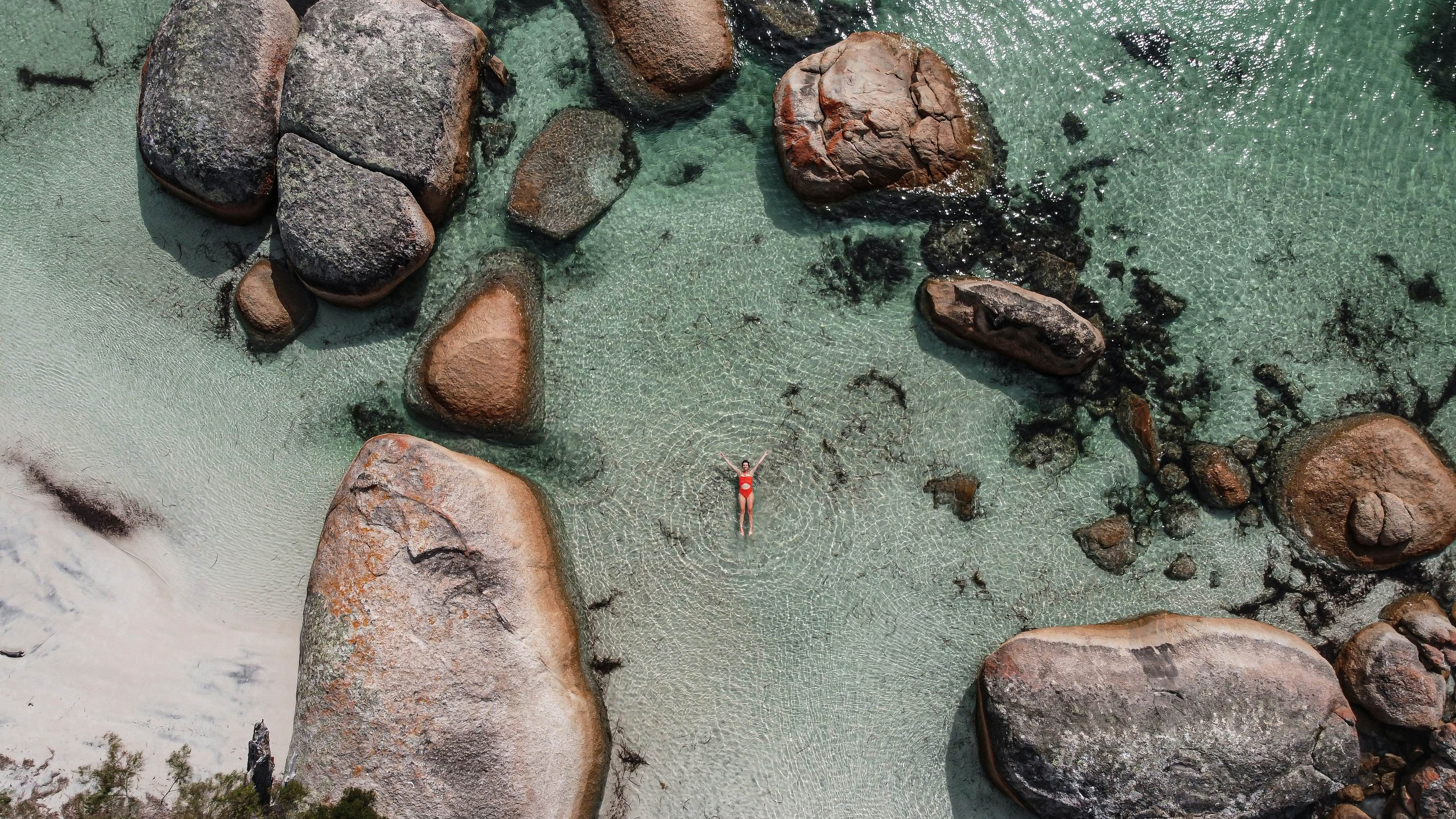 Aerial picture of a girl swimming in a fairy pool in Albany, Australia. Shallow and transparent water. Drone picture. Swimming in paradise in blue water between rocks.  License Type: media  Download Time: 2024-04-03T17:21:01.000Z  User: nic.dhoedt_lonelyplanet  Is Editorial: No  purchase_order:   