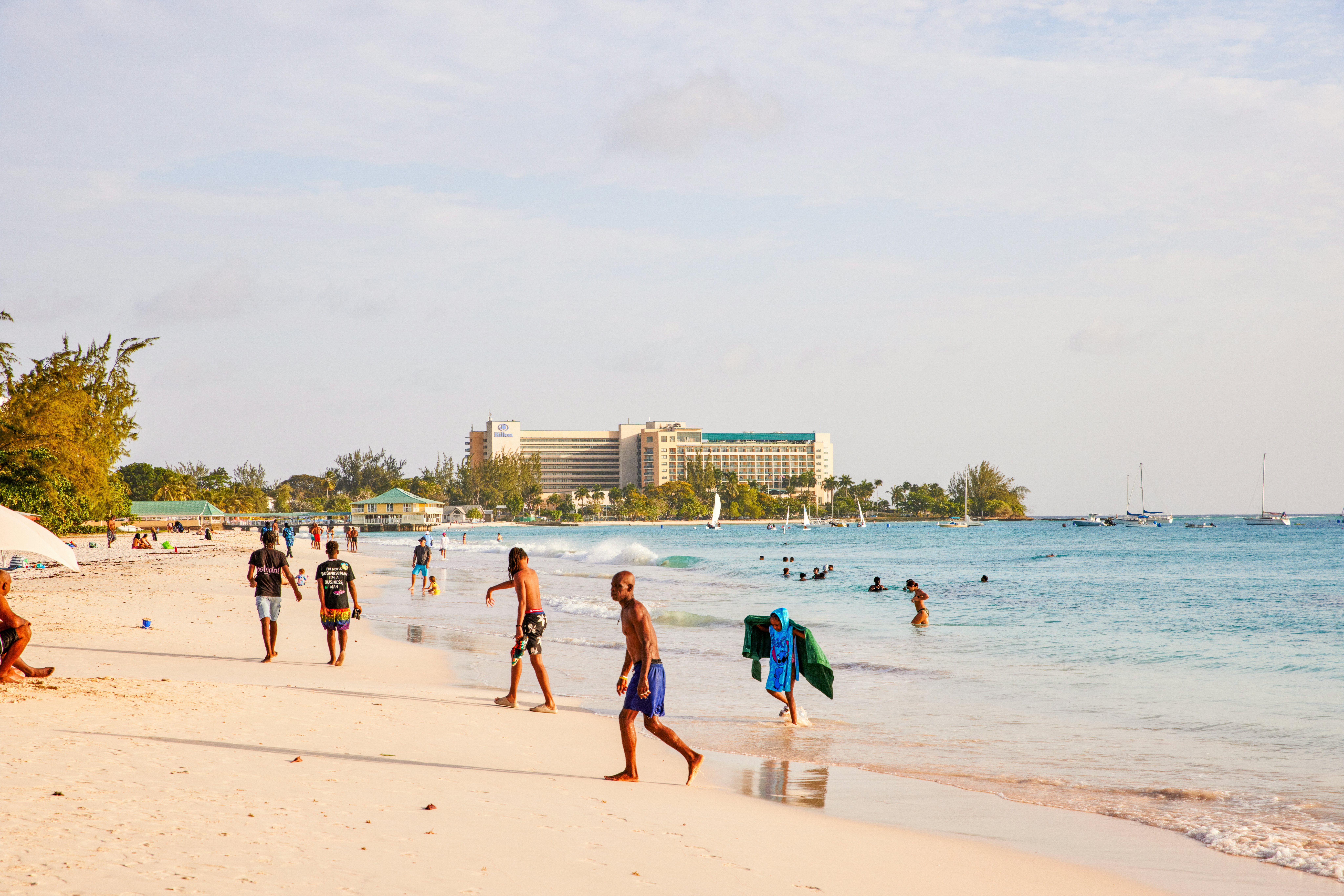 People scattered on a beach shore. Some are walking along the beach, others in the water, and some walking out of the water.