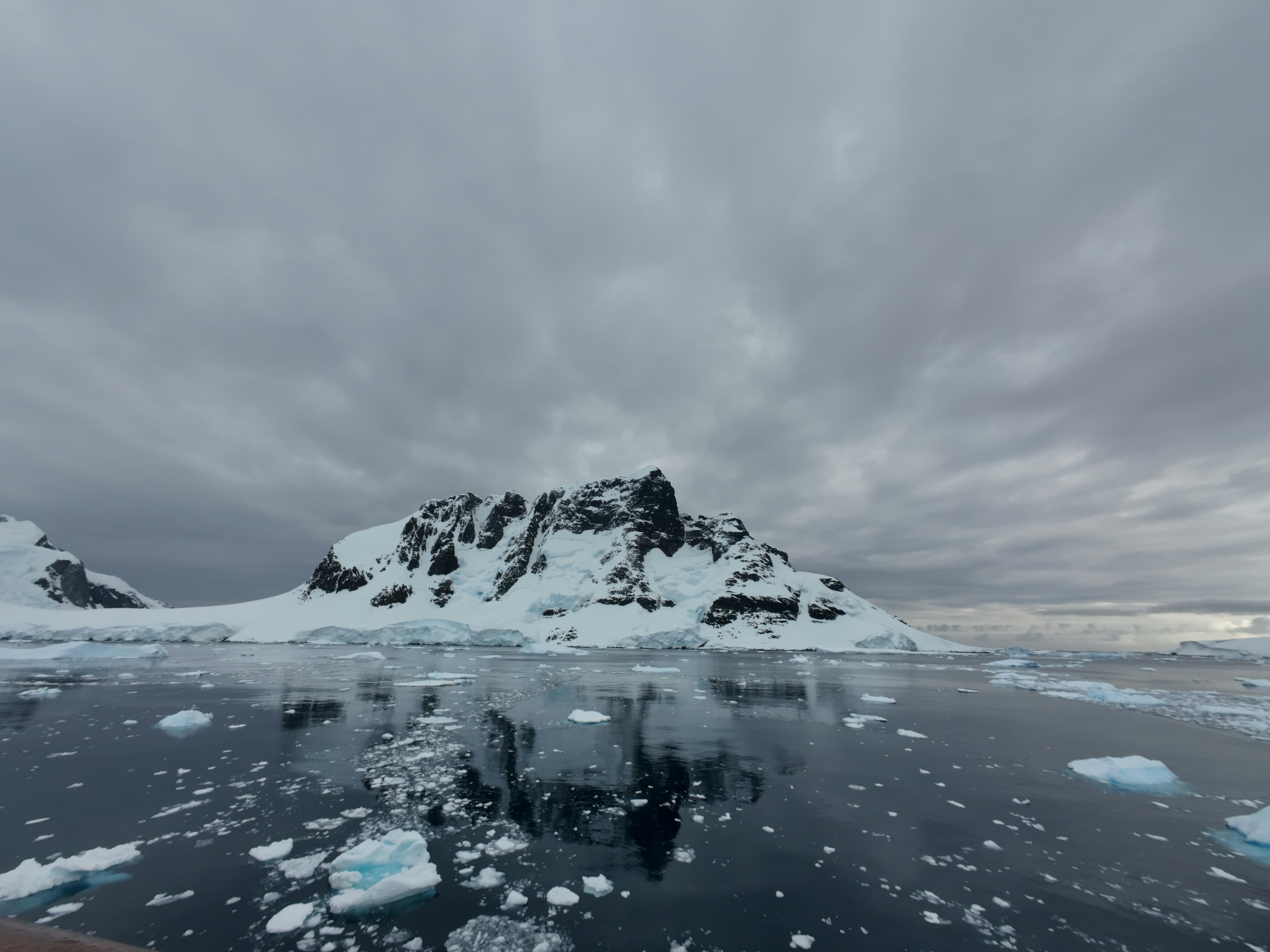 Snow-covered mountains and water on an overcast day in Lemaire Channel, Antarctica