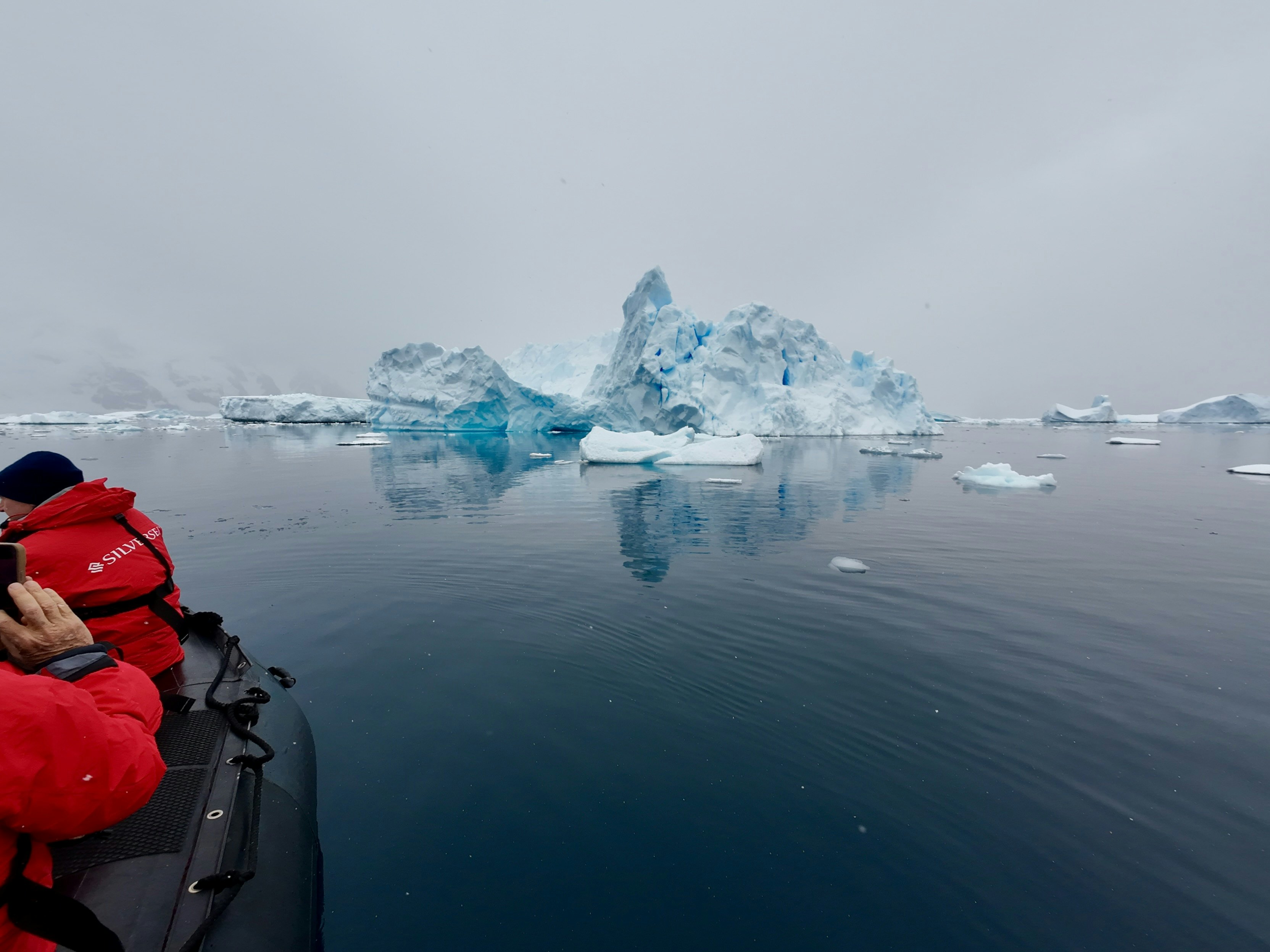 Lemaire Channel, Antarctica, with snow-covered mountains in the background and people in a raft in the foreground
