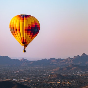 A lonely hot air balloon flies over Phoenix Arizona with the Sonoran Desert in the background.; Shutterstock ID 1176204118; purchase_order:65050 - Digital Destinations and Articles; job:Online editorial; client:Guide to Phoenix refresh; other:Ann Douglas Lott
1176204118