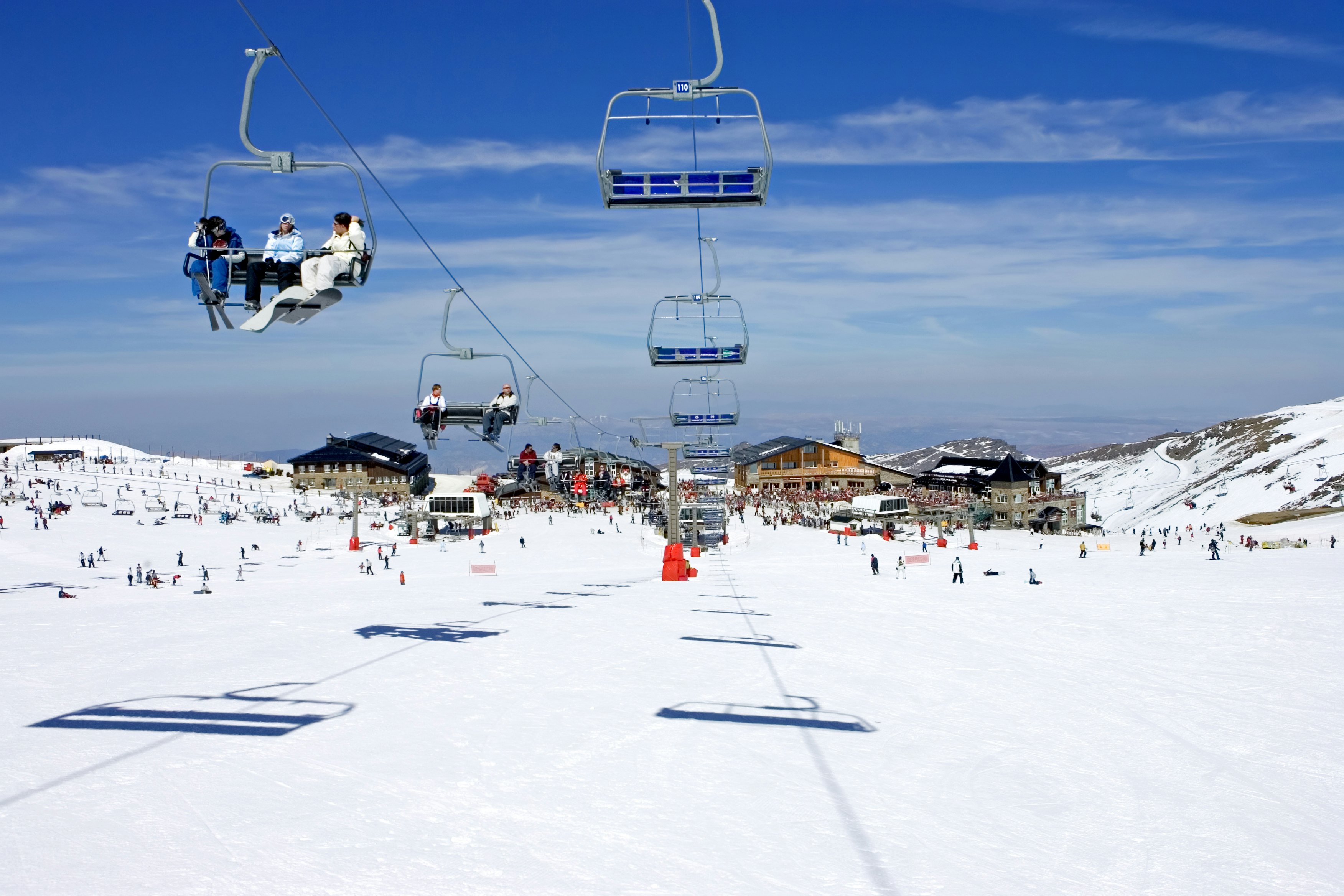 Ski slopes and chair lifts at a snow-blanketed resort under a blue sky