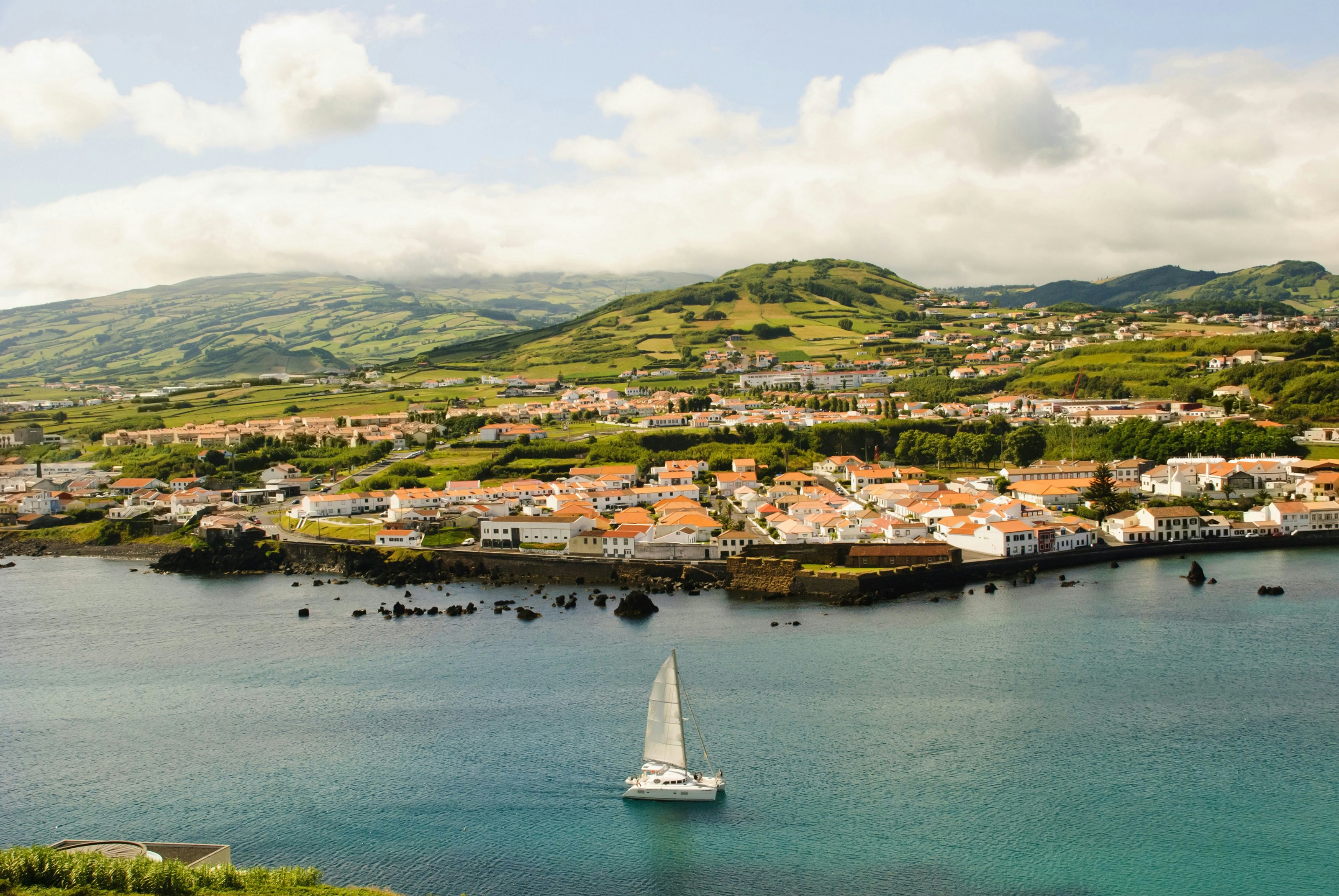 View to Horta with bay, Faial island, Azores, with a catamaran in the water in the foreground