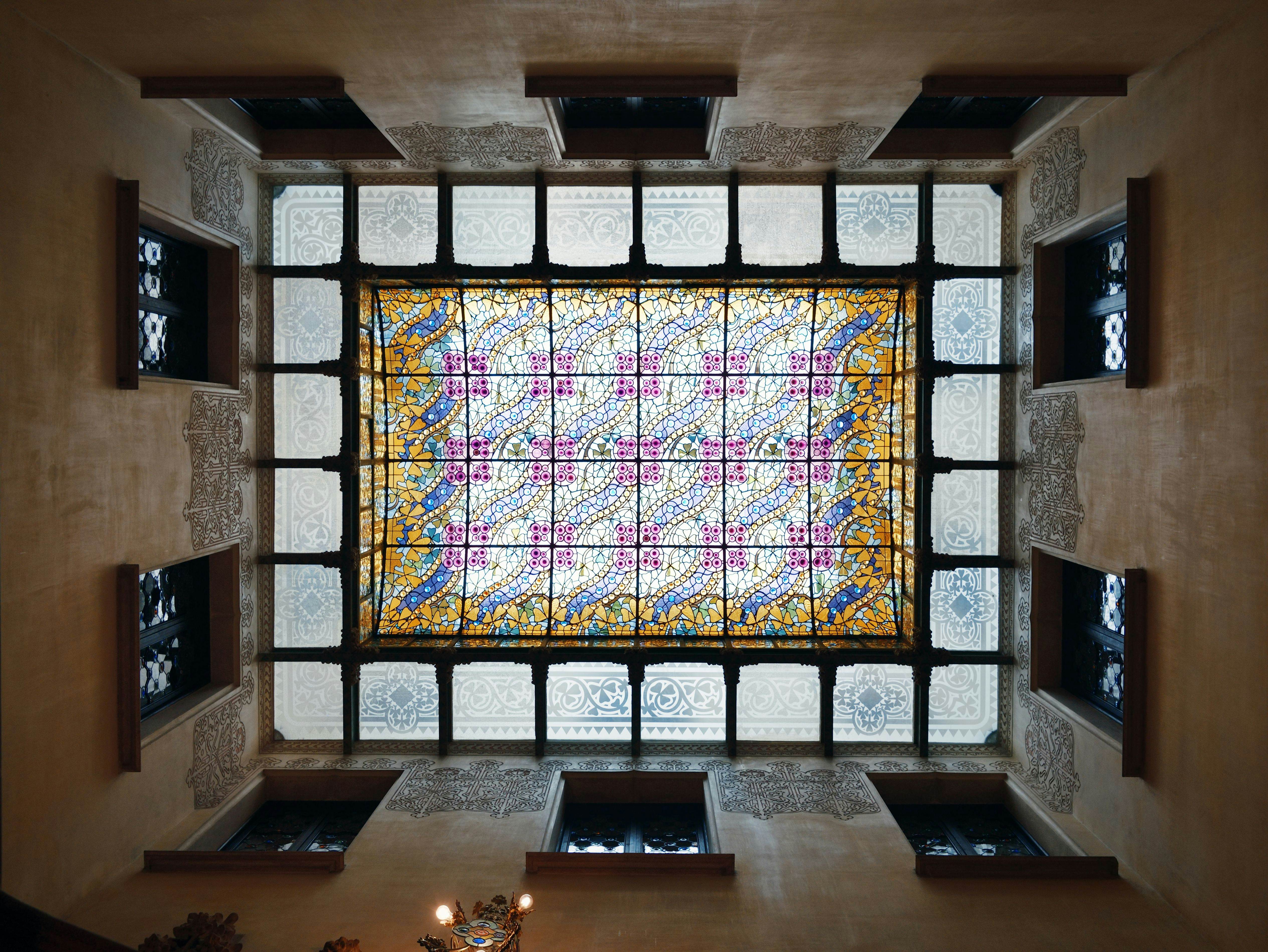 A stained glass ceiling with a colorful central design surrounded by smaller panels on the perimeter.