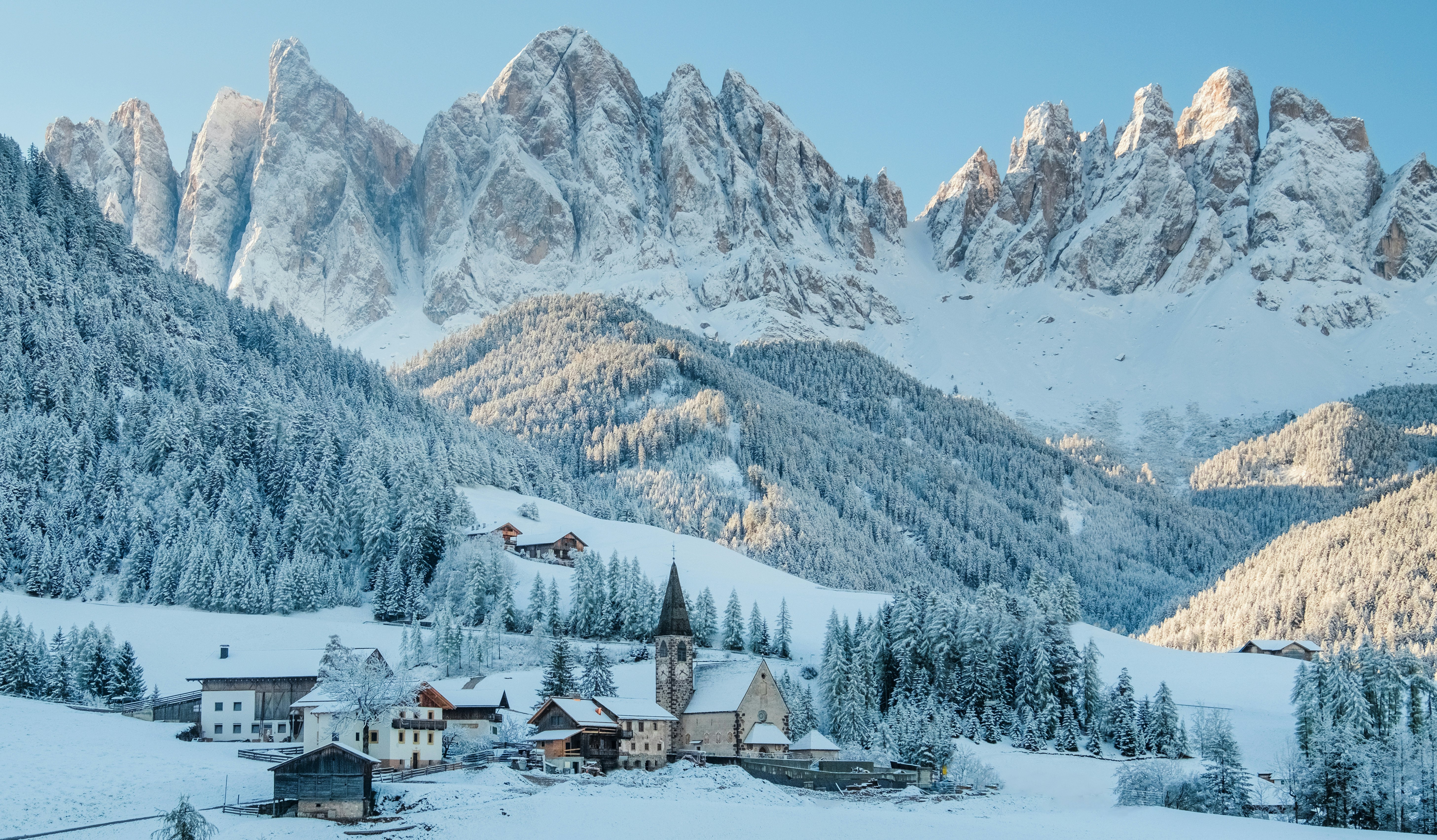 The small village of Val di Funes covered in snow, with the Dolomites mountains in the background