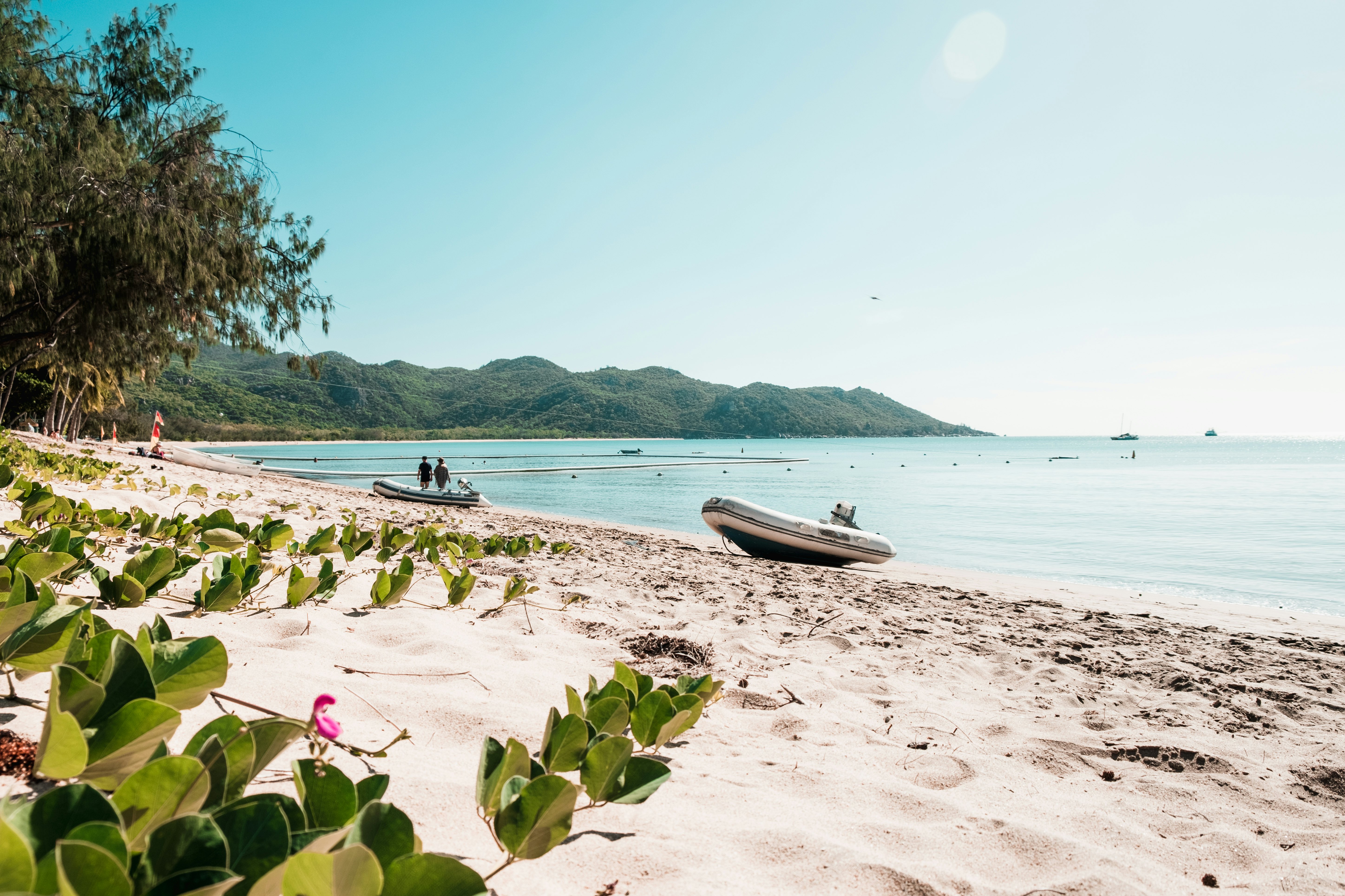 Two empty inflatable boats resting on a sandy beach of a tropical island.
