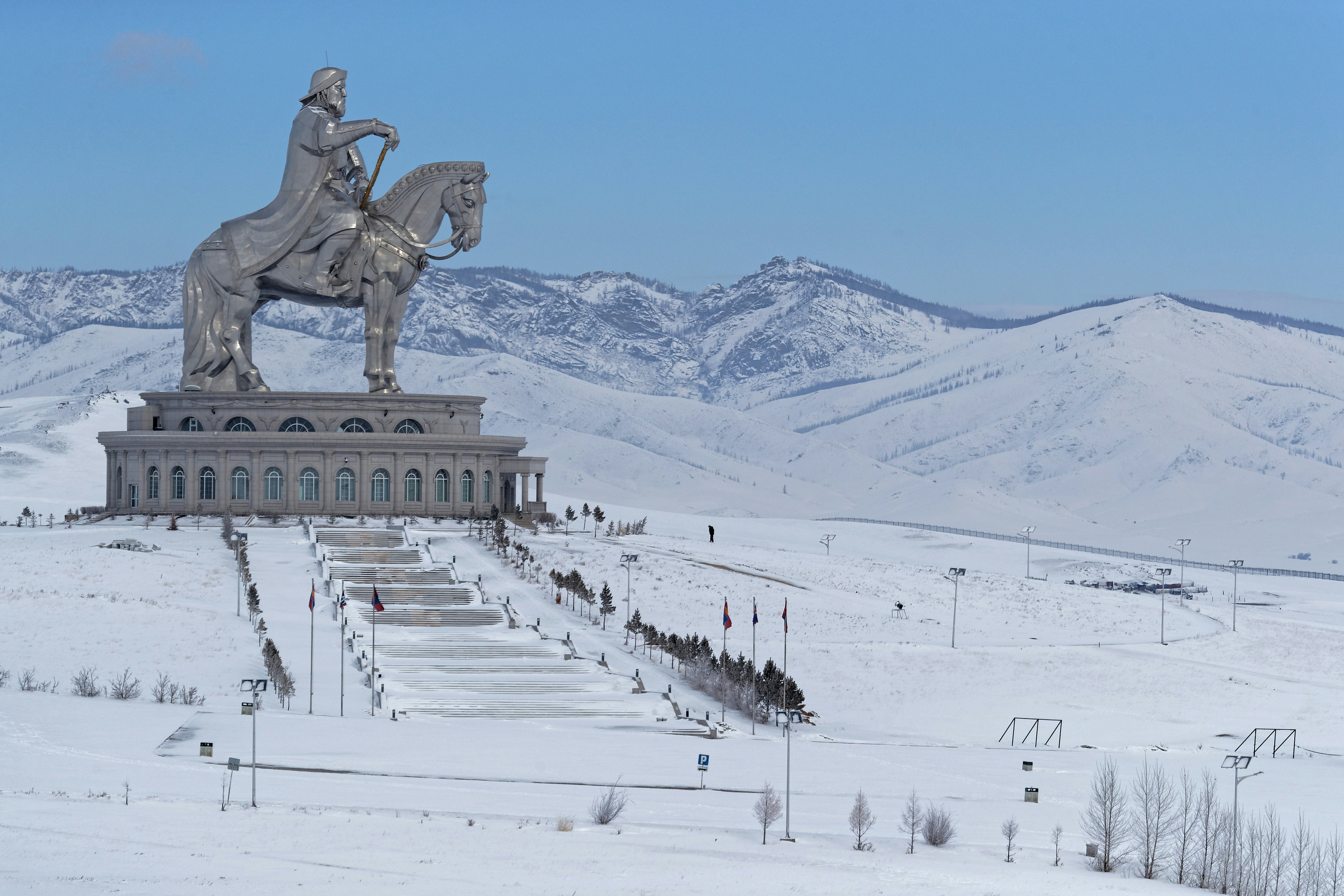 A huge steel statue of a man on horseback towering over a snow-covered hillside.