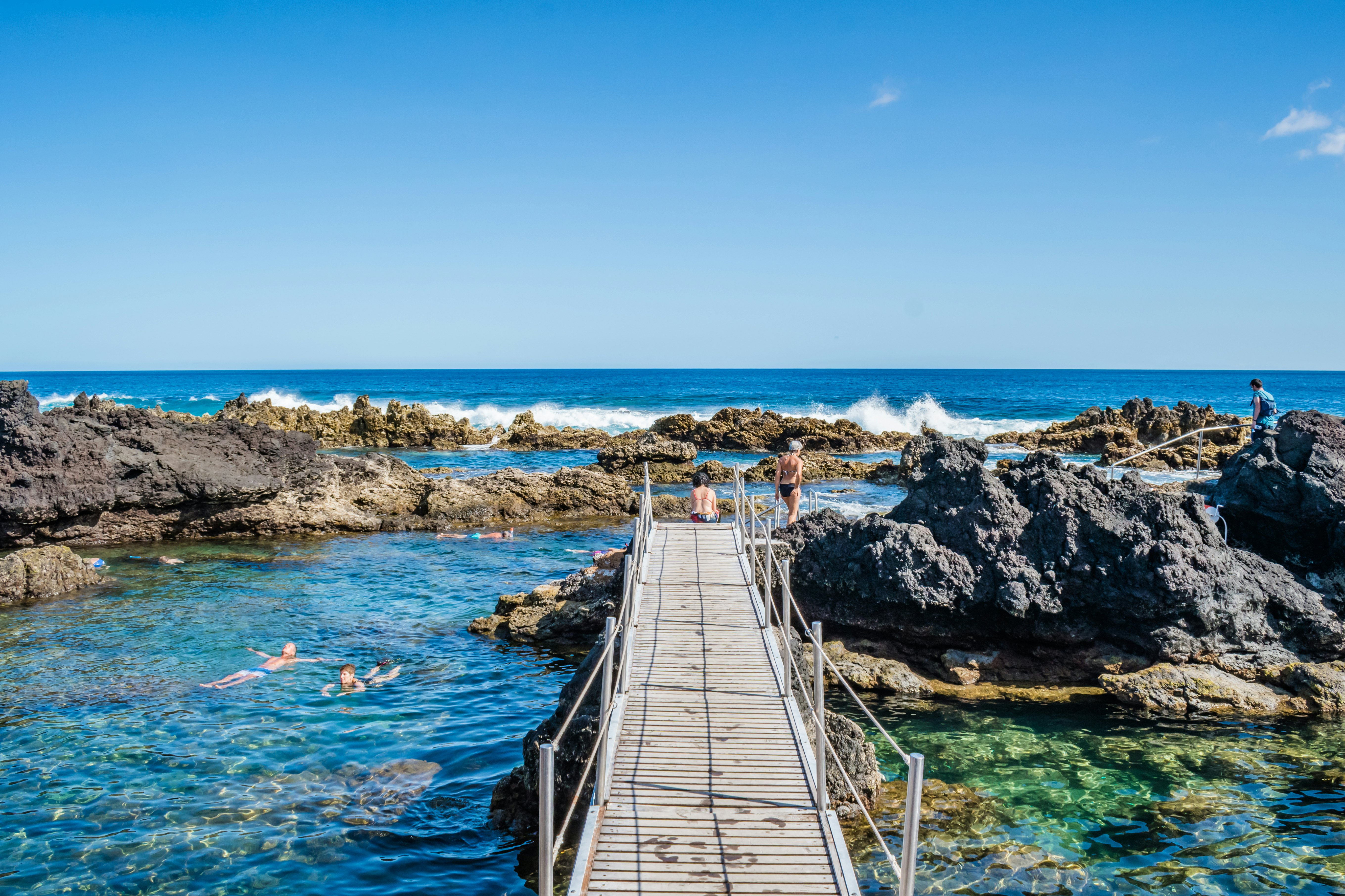 Terceira, Azores PORTUGAL, Wooden bridge for natural pools among volcanic rocks in Biscoitos with tourists at leisure