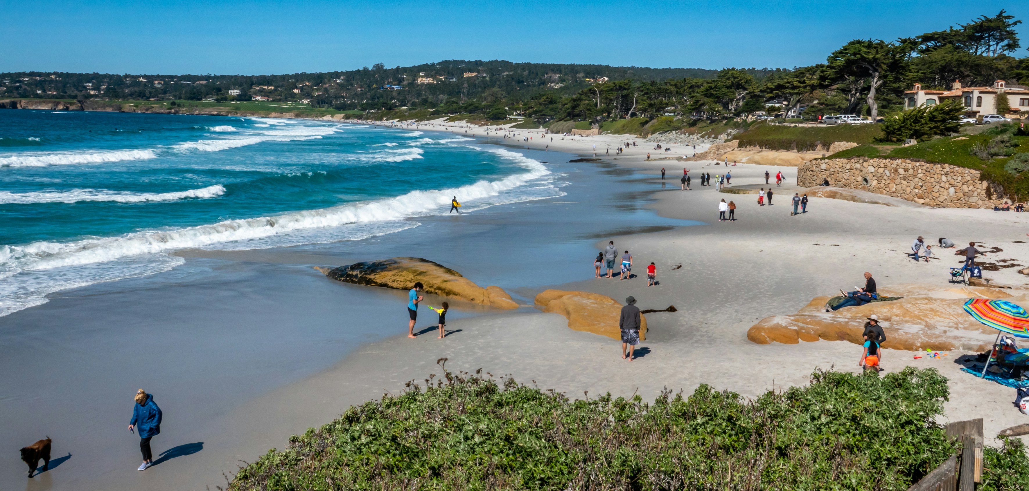 Families and dog walkers enjoy the sandy shores of Carmel Beach, along the Monterey Bay of the central California coast.