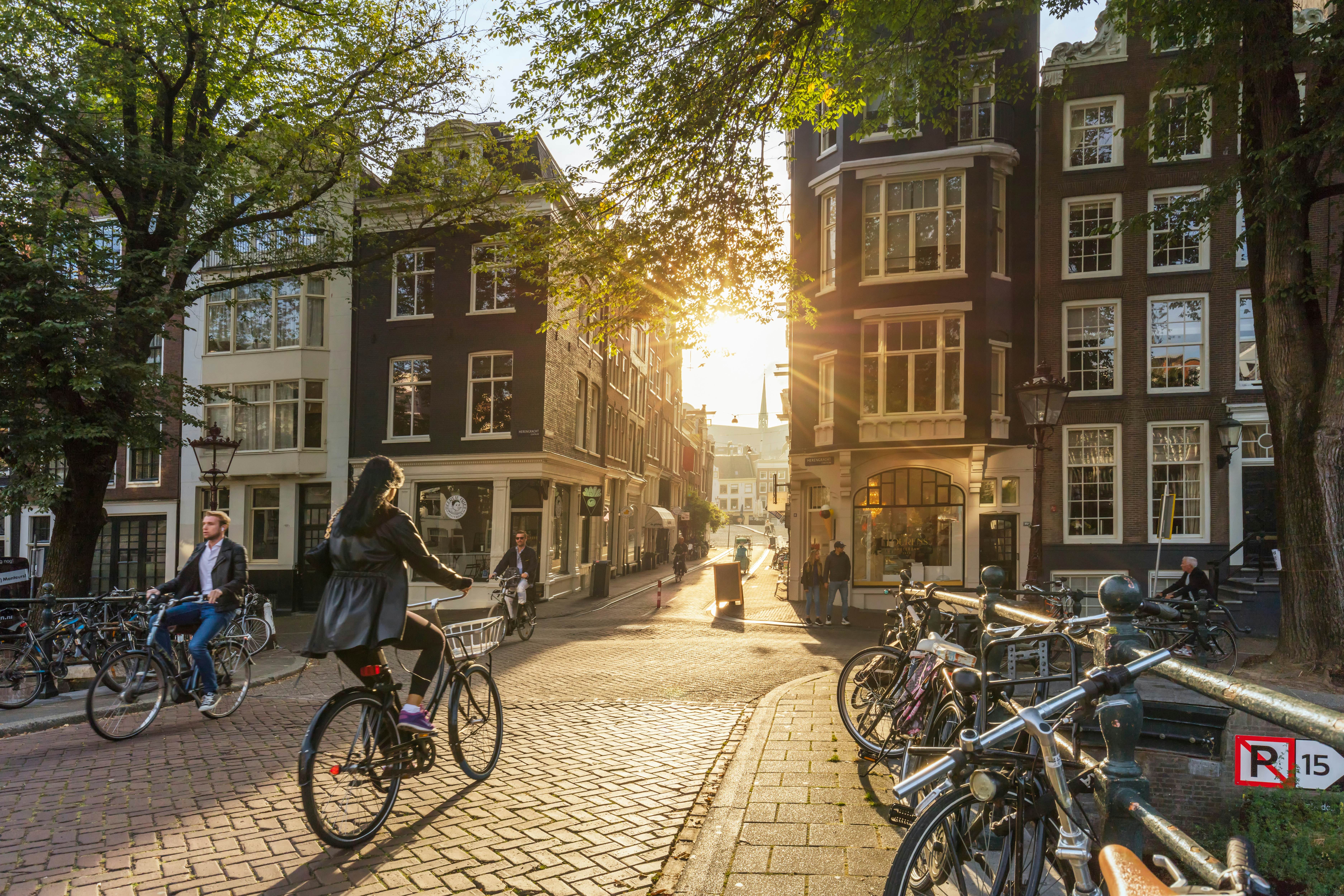 People ride bicycles silhouetted by the early morning sun in Amsterdam