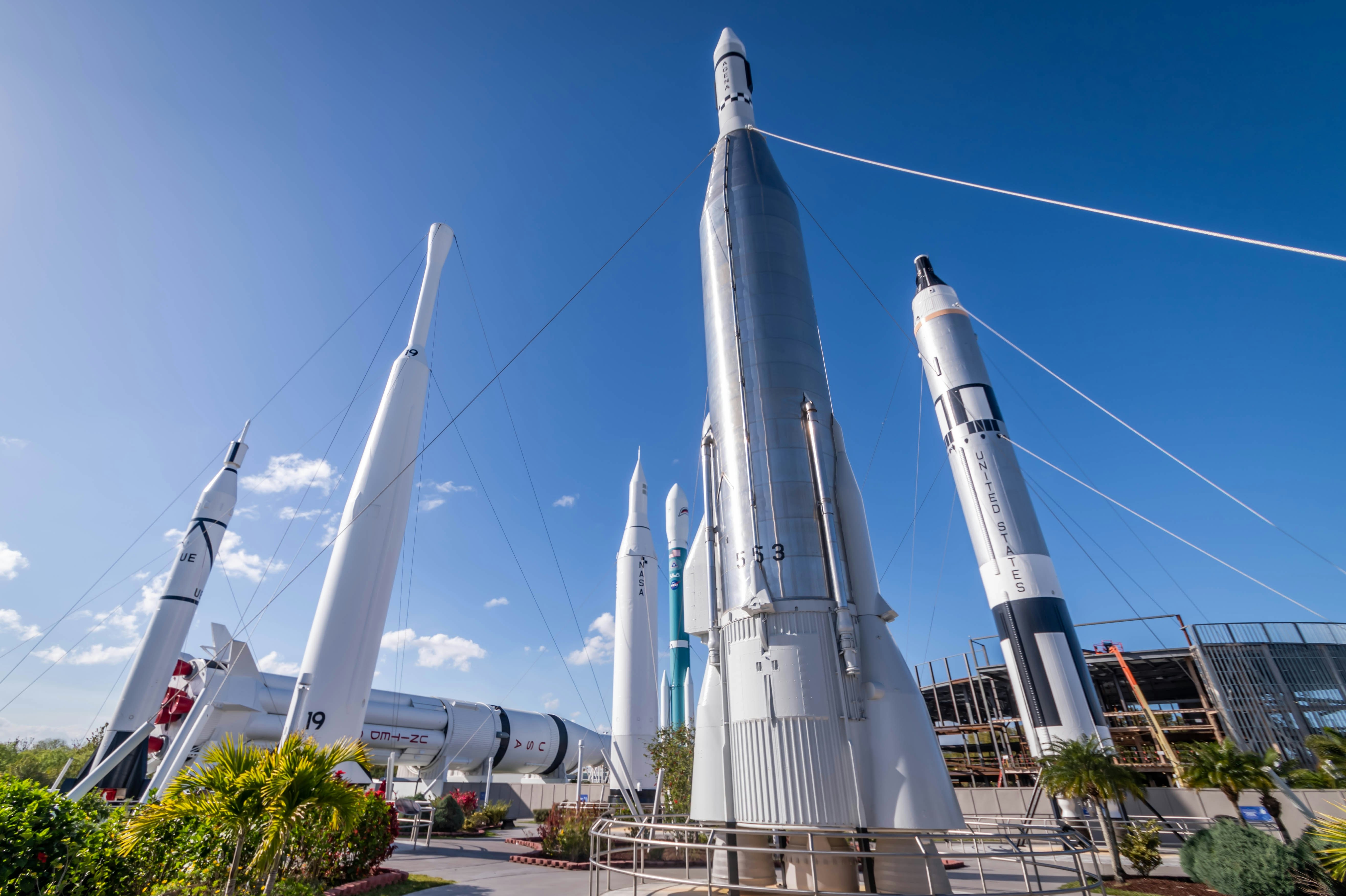 A series of space rockets standing tall in an outdoors display at a space museum.