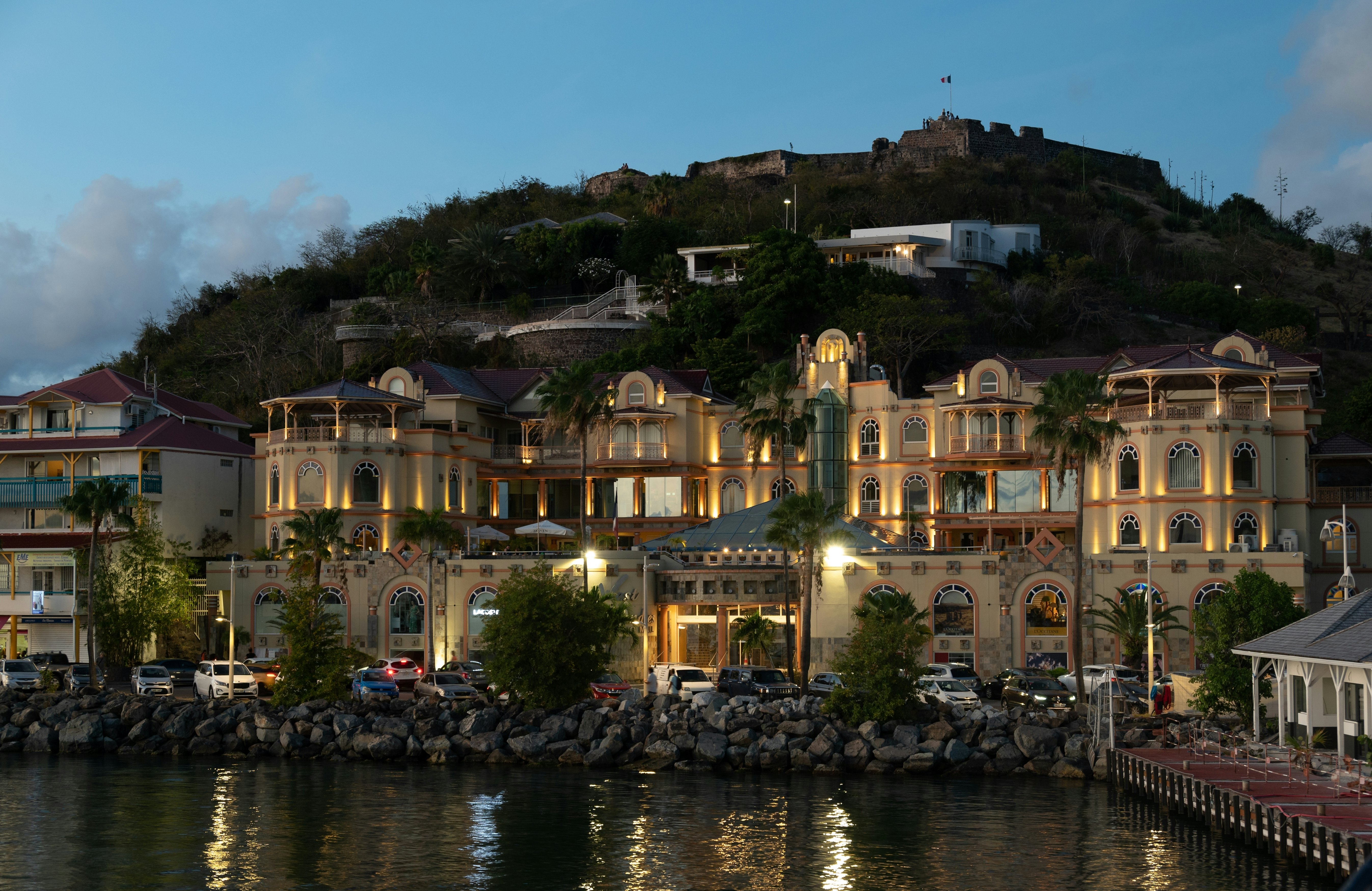 Buildings along the port of a village are illuminated at dusk.