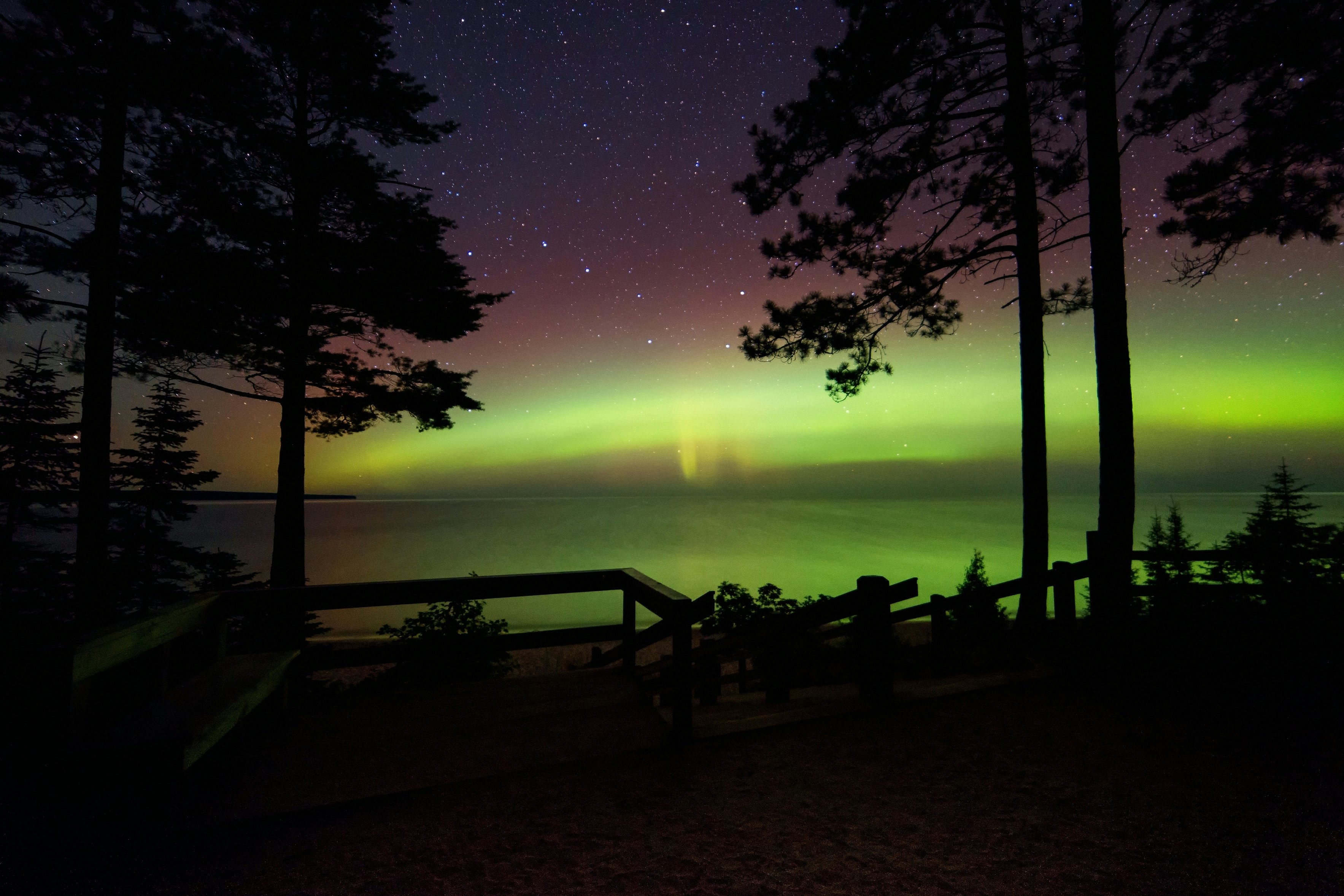 The Big Dipper over a lake with the northern lights along the horizon.