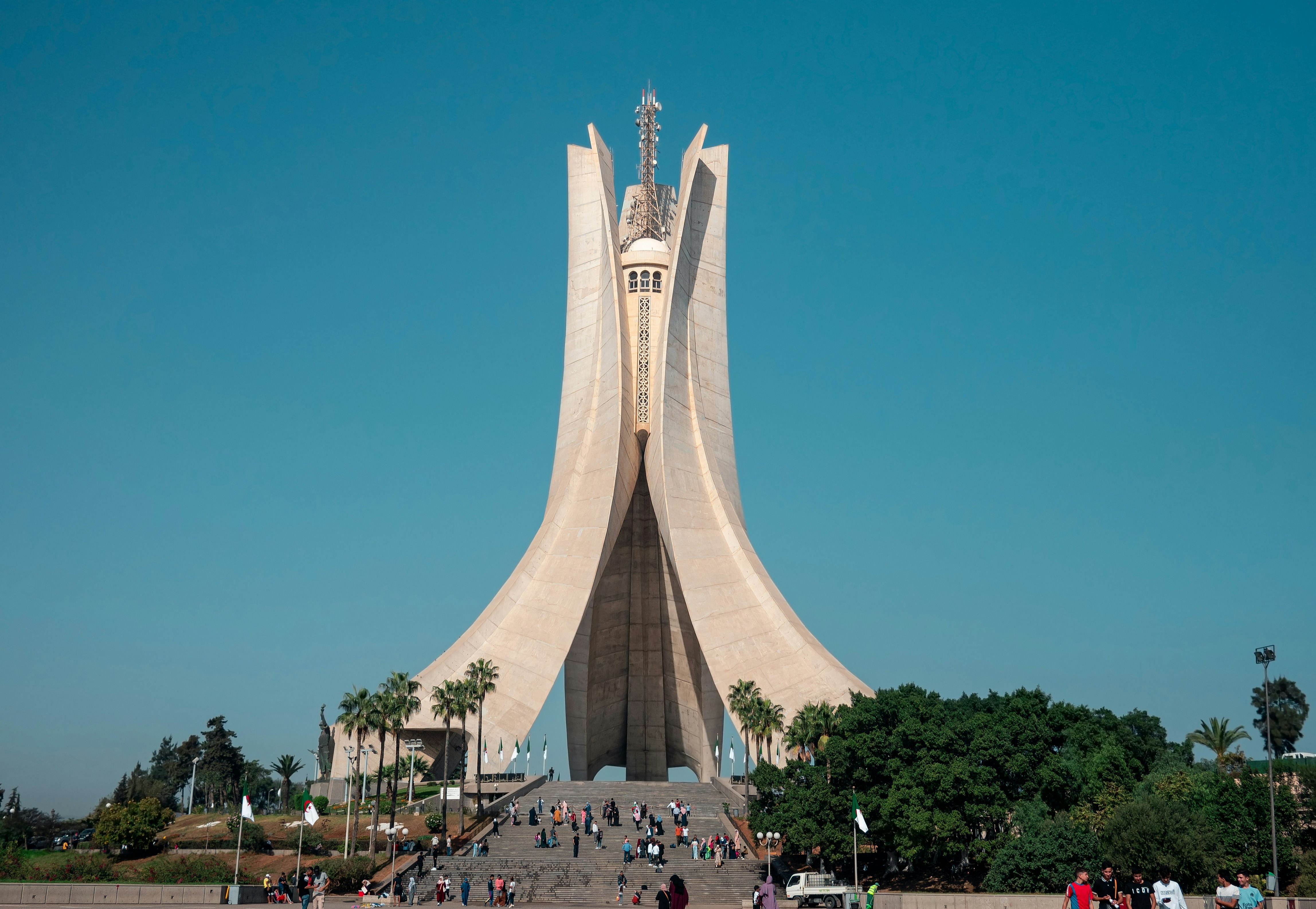 People gather on the steps of a concrete monument that stretches high into the sky.
