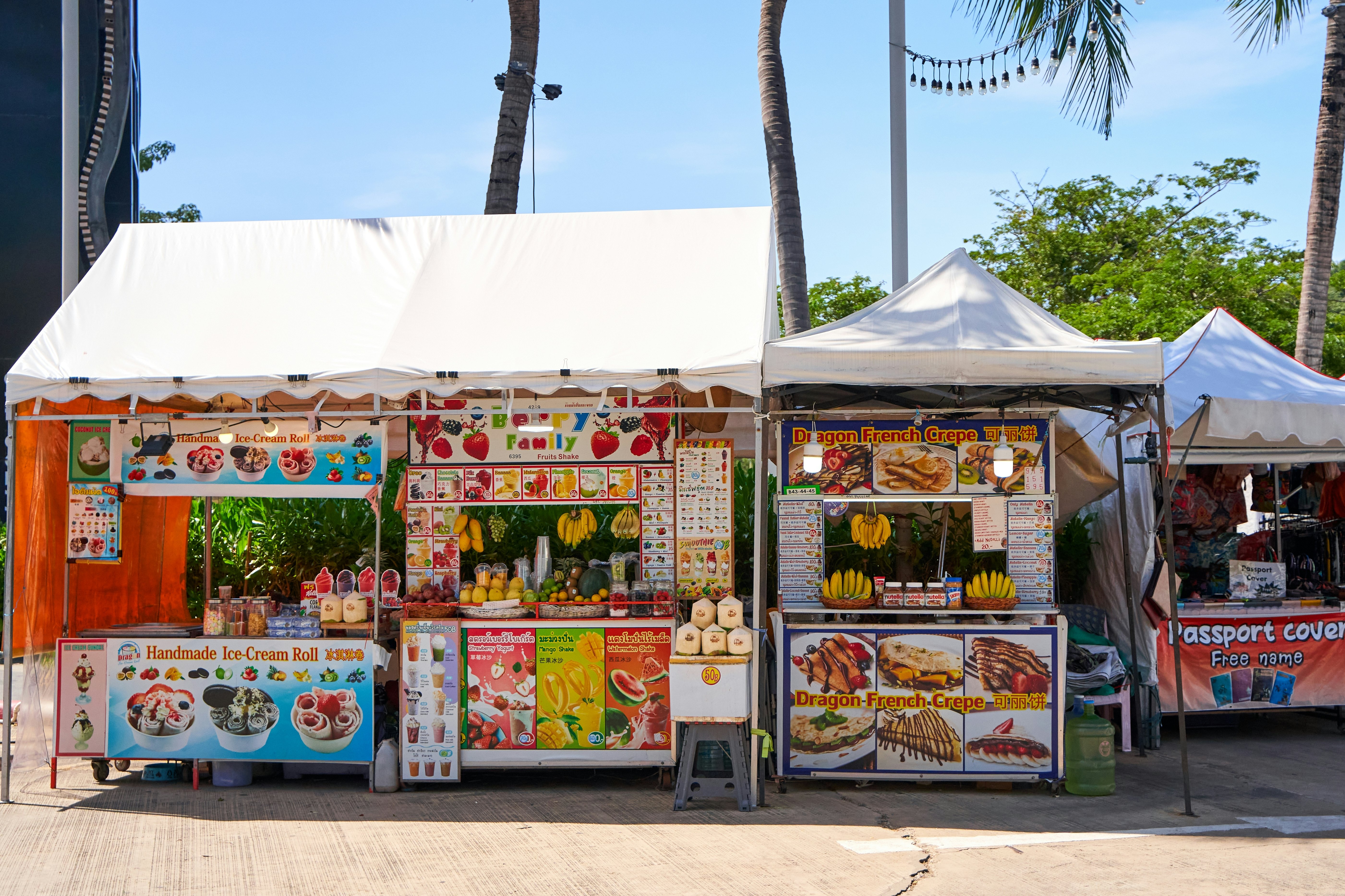 Three roadside food stalls selling ice cream, fruit shakes and crepes.